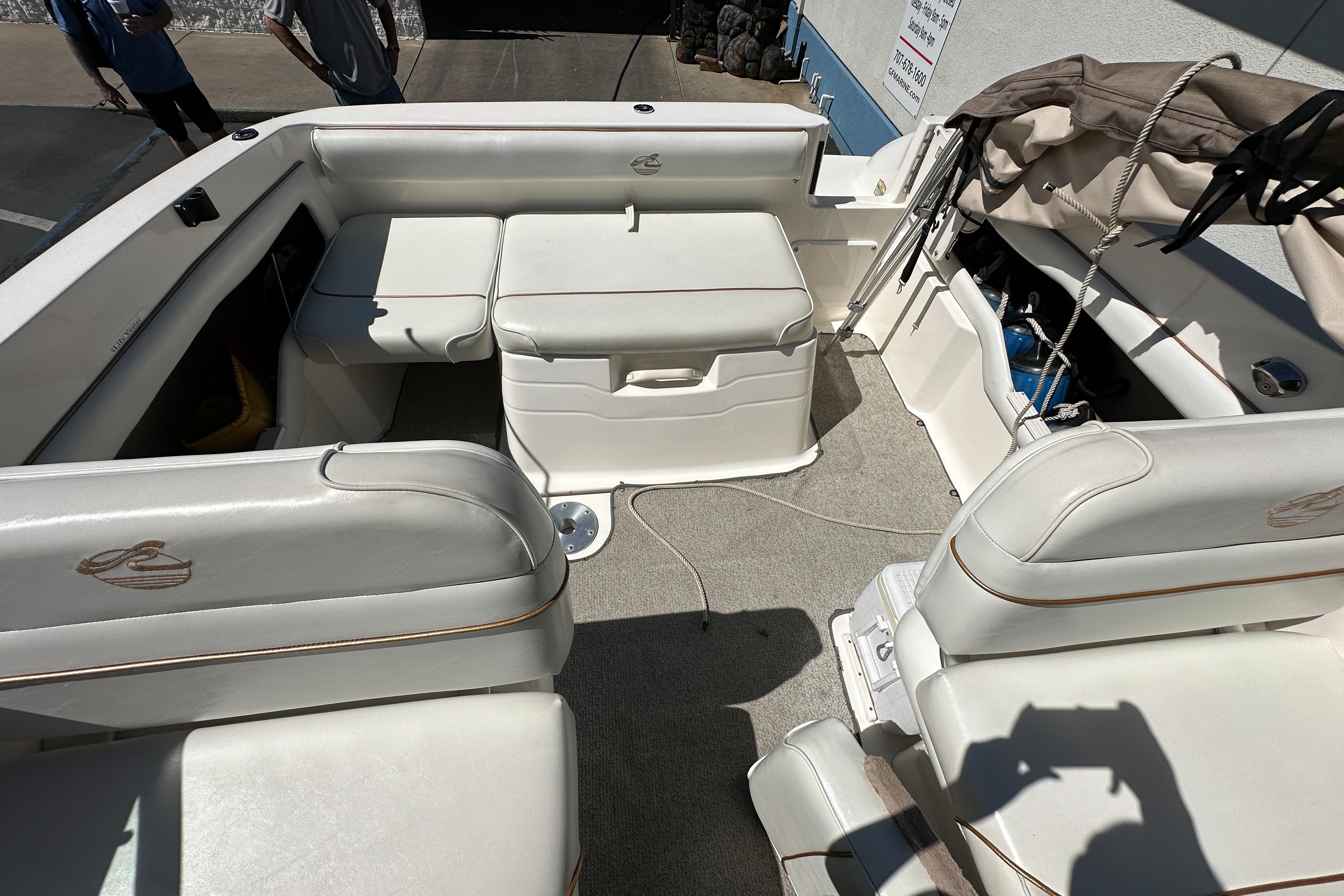 1998 Sea Ray 215 Express Cruiser interior with white seating and storage compartments.