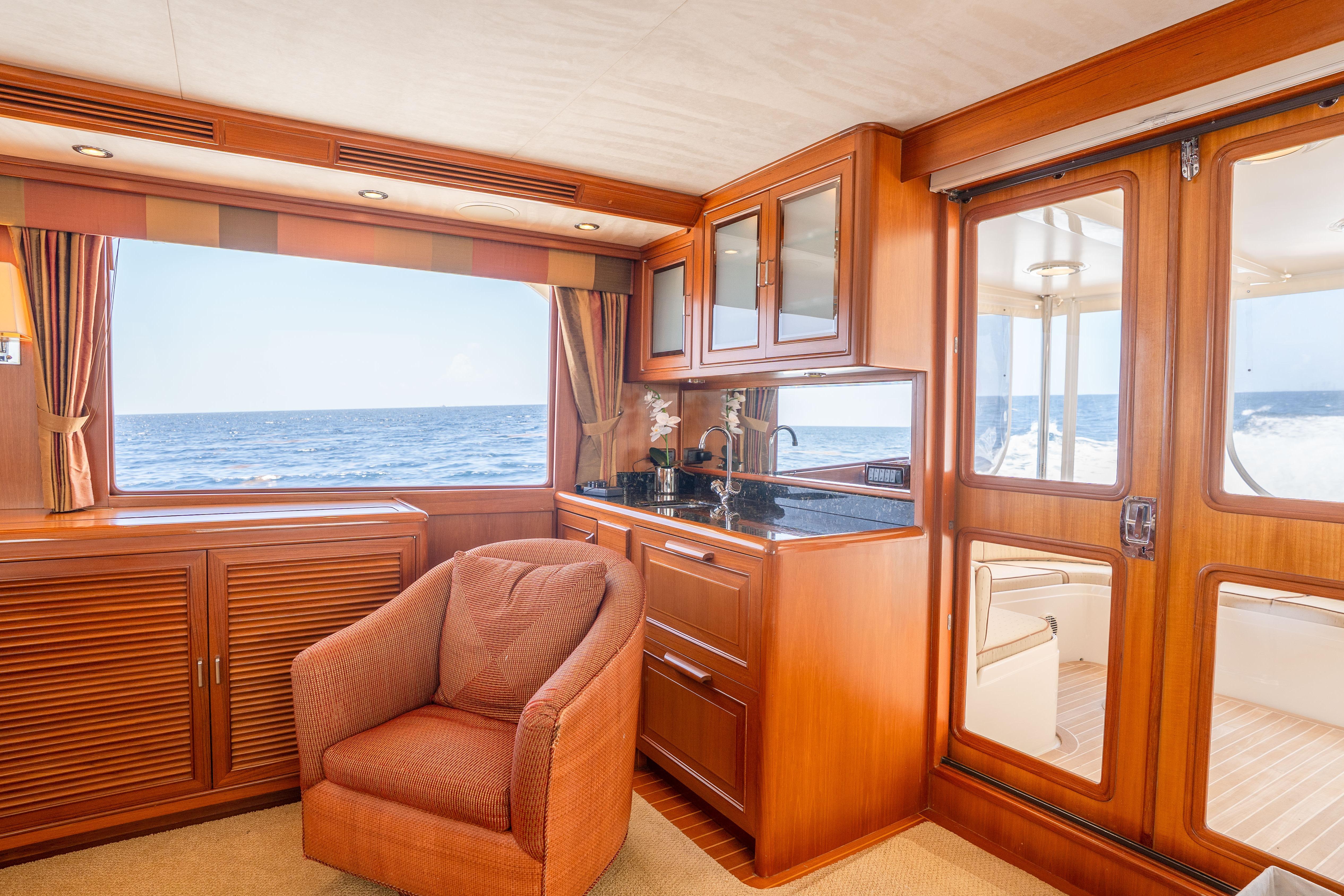 Luxurious interior of 2006 Fleming 75 yacht with ocean view, featuring elegant wood finishes.
