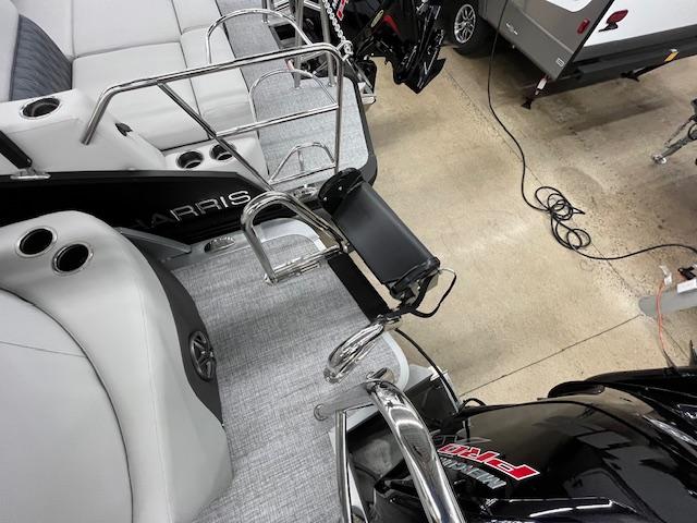 2025 Harris Cruiser 210 boat interior with seating and railing in a showroom.