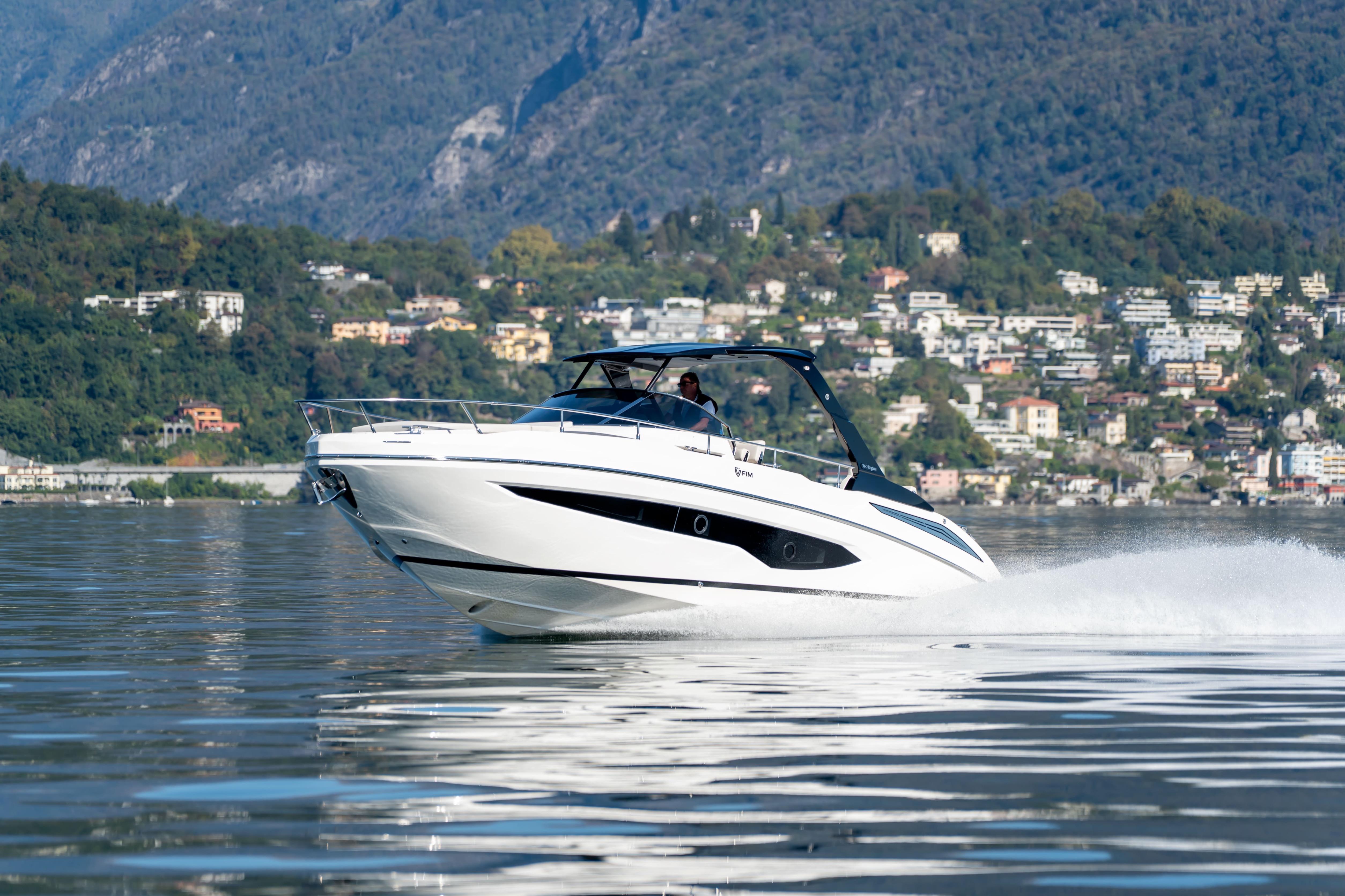 2026 FIM 340 Regina IB cruising on a scenic lake with mountains in the background.
