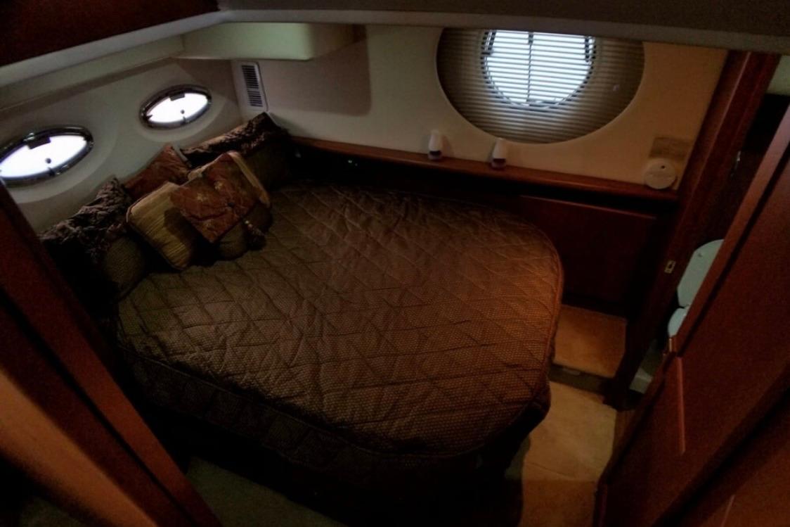Cozy bedroom interior of 2006 Silverton 35 Motor Yacht with plush bedding and porthole windows.