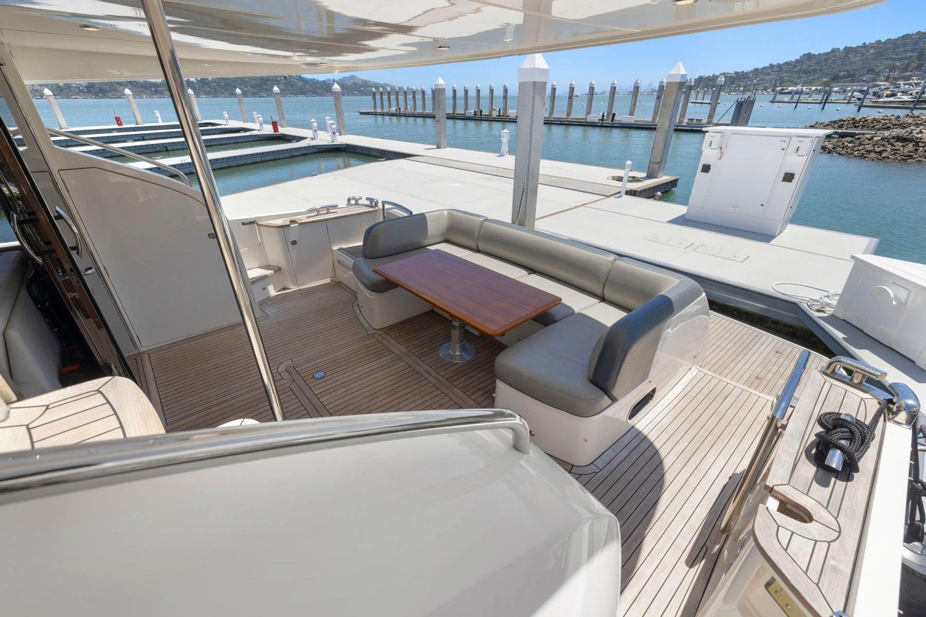 Luxurious 2015 Princess 60 Flybridge Motor Yacht with elegant outdoor seating and scenic marina view.
