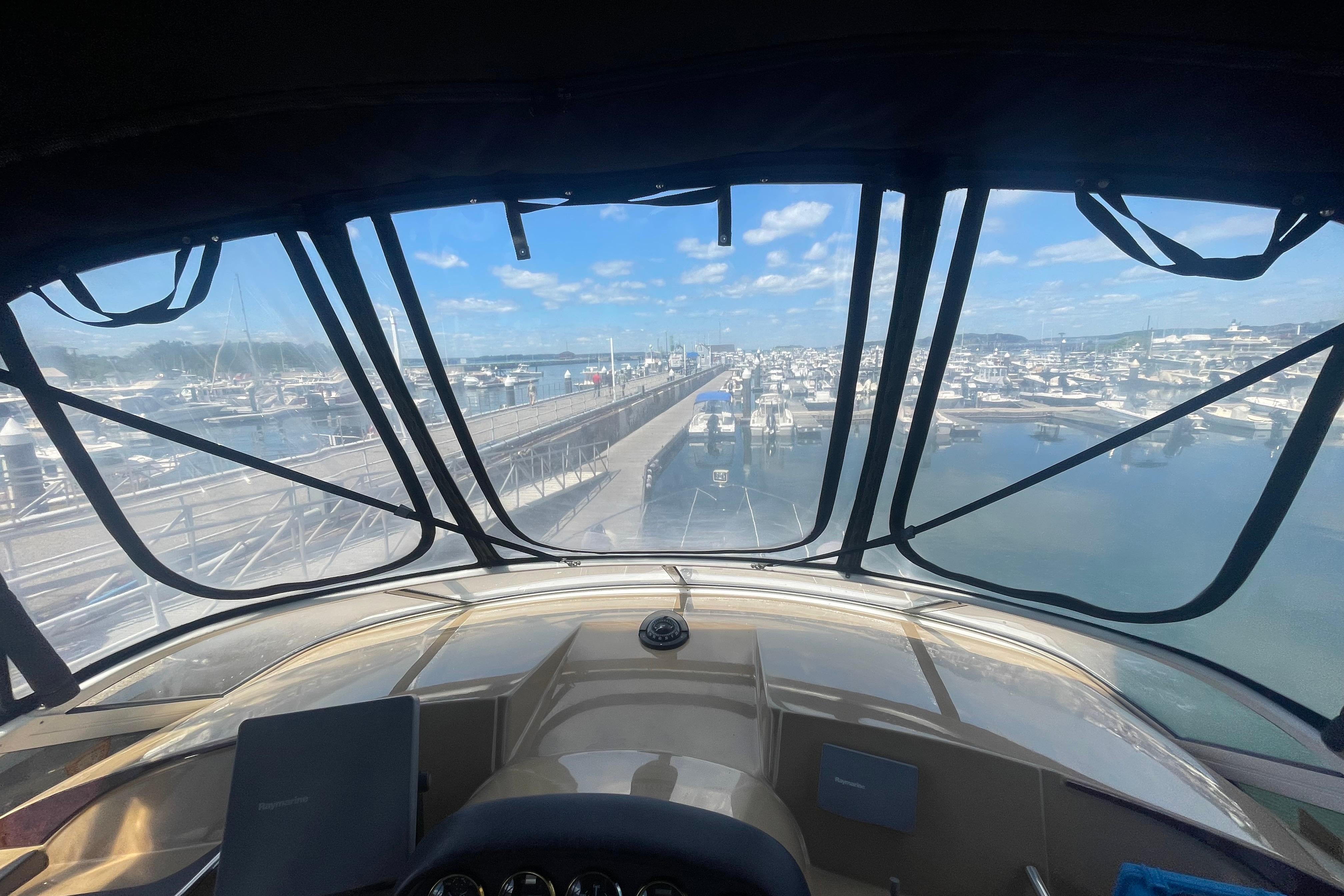 View from 2002 Carver 410 Sport Sedan cockpit overlooking marina and docks on a sunny day.