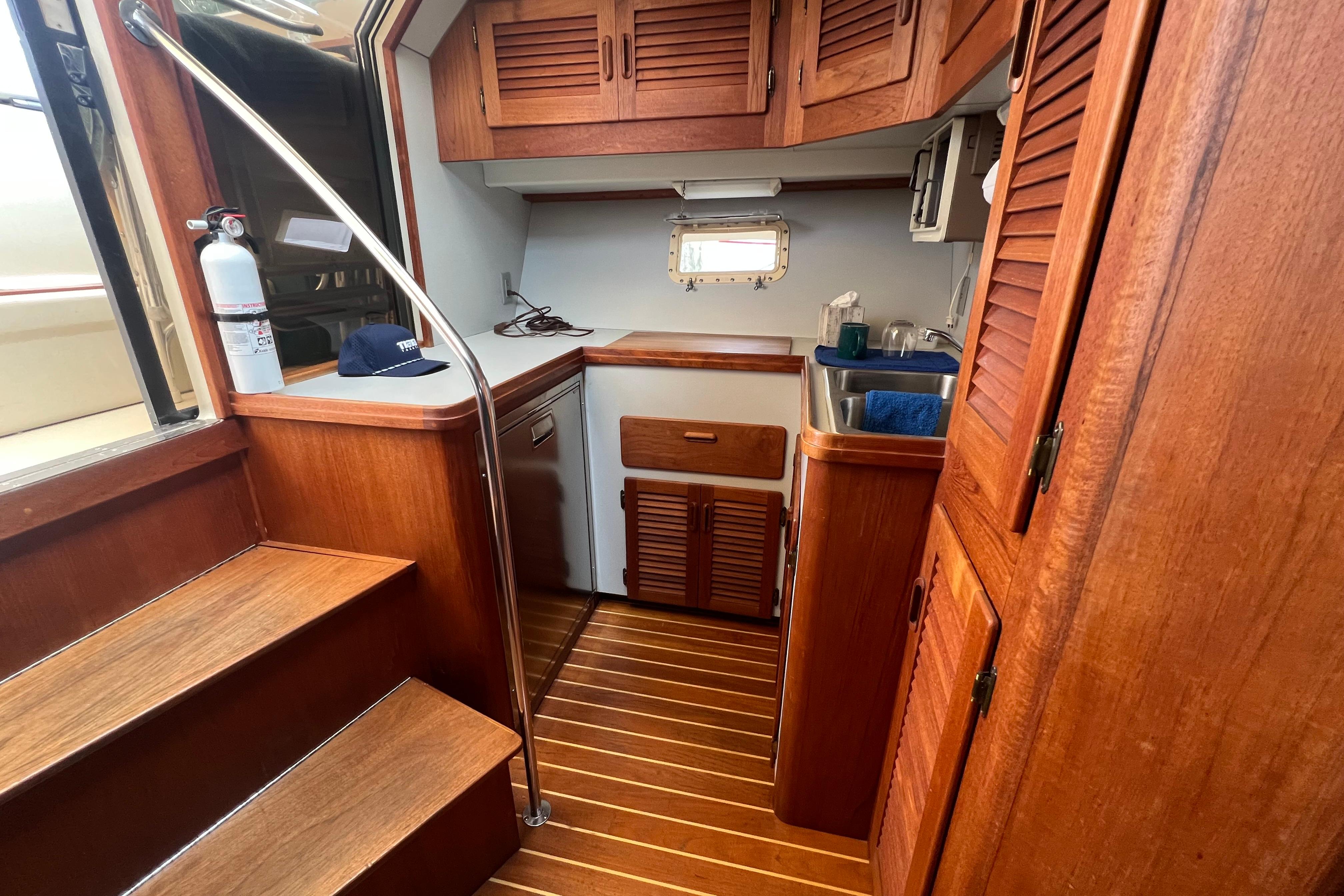 Interior of 1985 Tiara 36 OPEN yacht with wooden cabinetry and compact kitchen area.