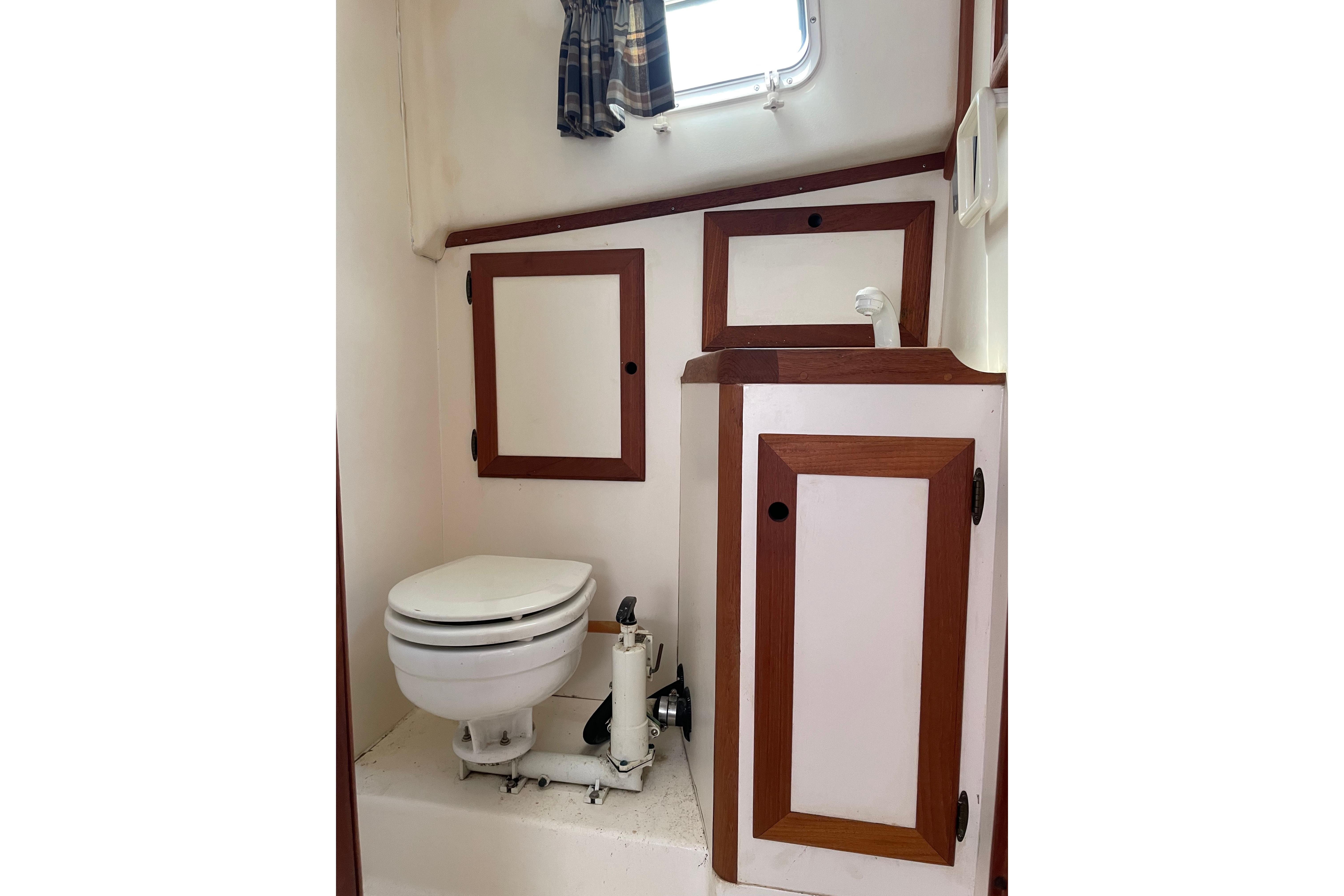 1988 Cape Dory Hardtop boat bathroom with wooden cabinets and a compact toilet.