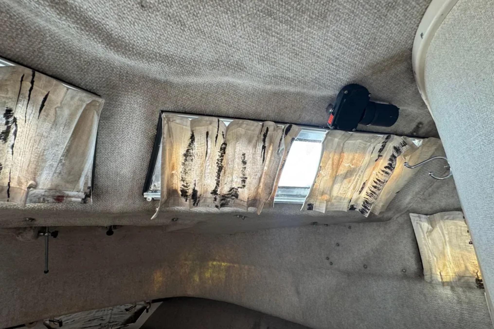 Interior cabin of 1990 Grady-White Marlin 280 with worn curtains and ceiling details.