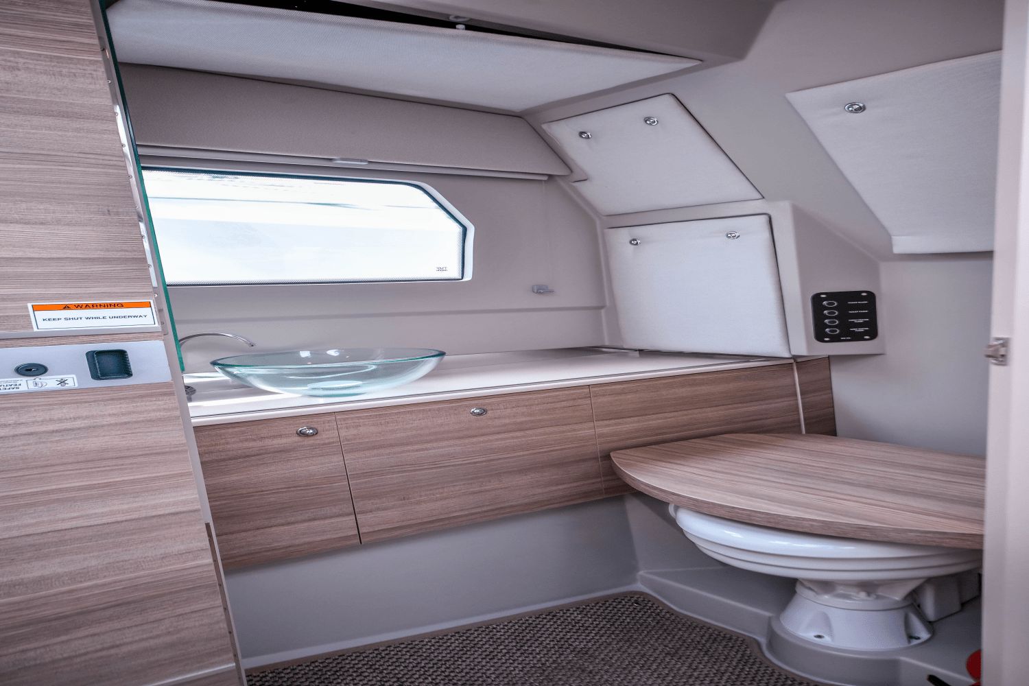 The image shows a modern boat bathroom with wooden cabinets and a glass sink.