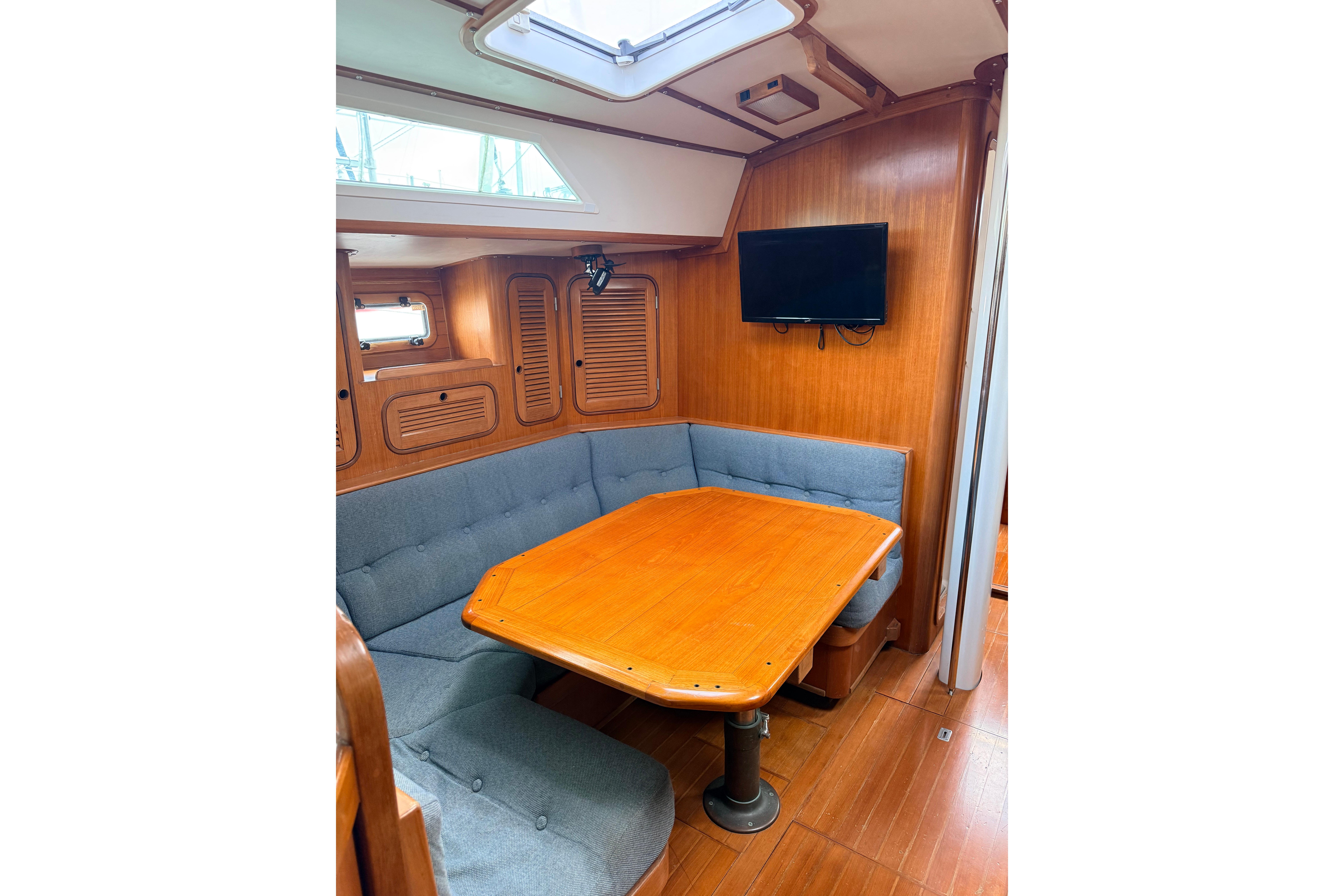 Interior of 1987 Norseman 400 sailboat with wooden dining area and cushioned seating.