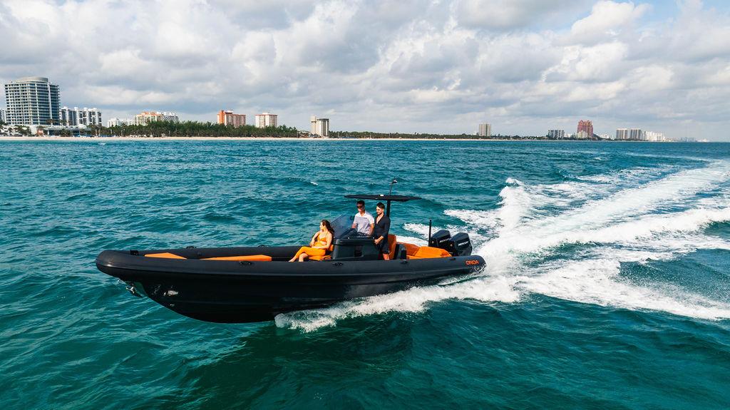2025 Onda Magna boat cruising on ocean near city skyline under cloudy sky.