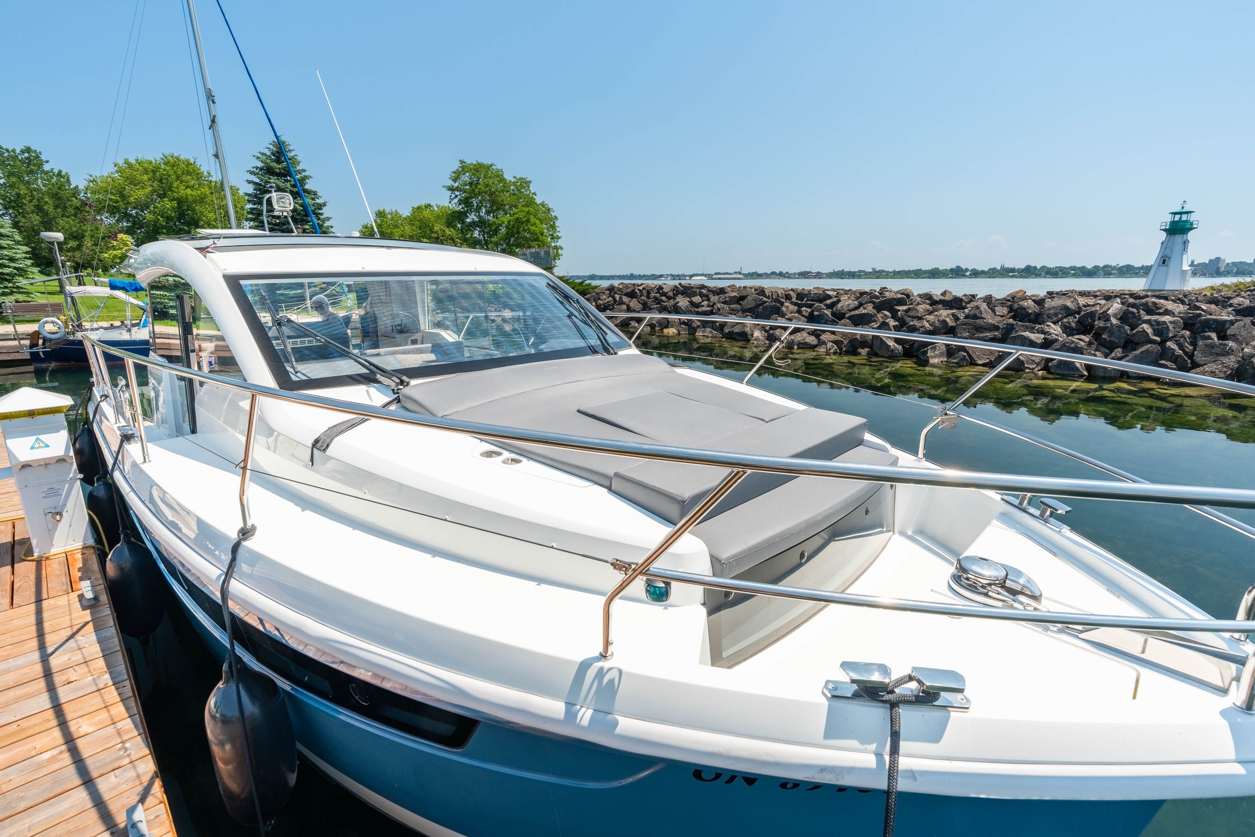 A modern Sealine C335V yacht docked with a view of a lighthouse.