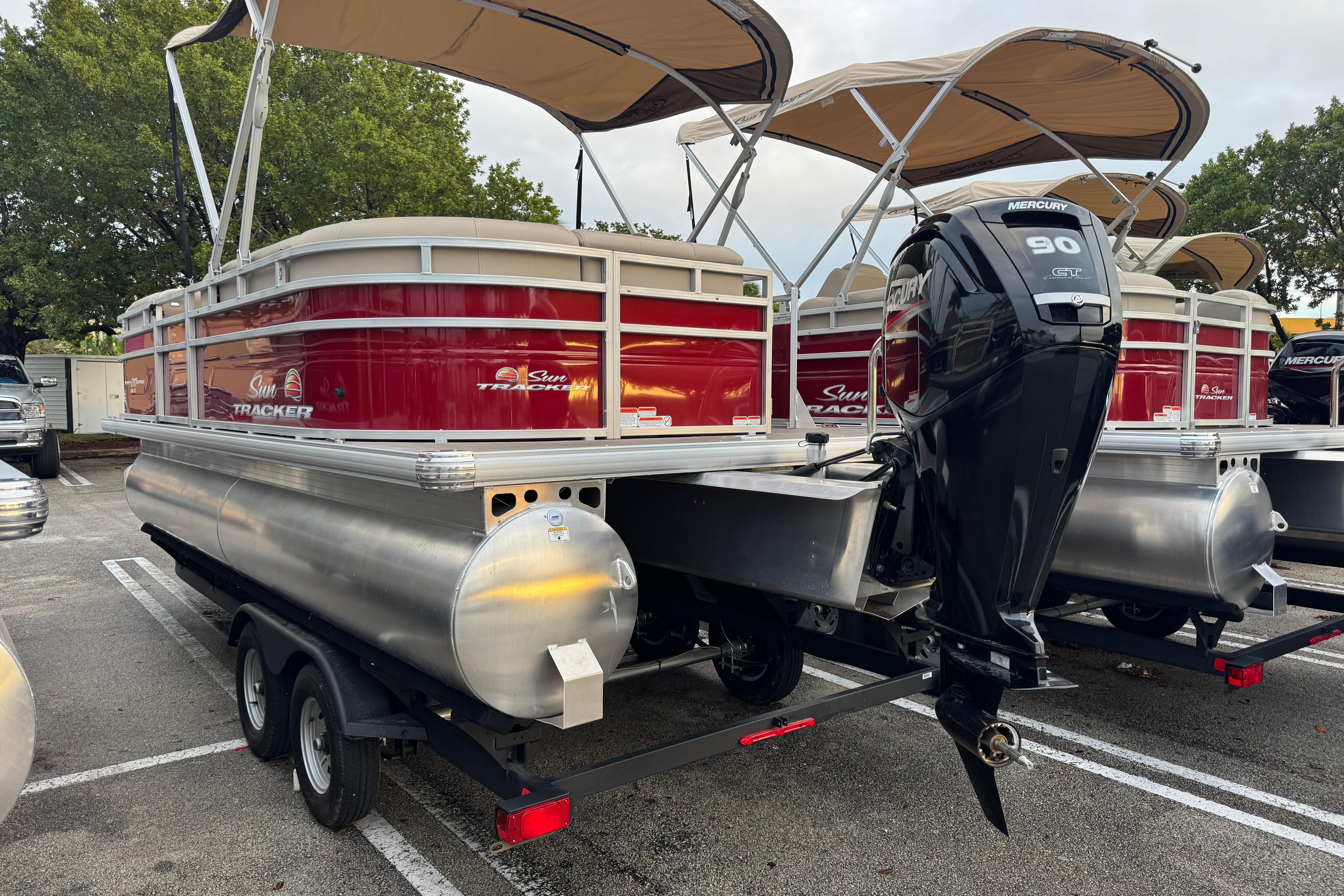 2025 Sun Tracker Party Barge 20 DLX pontoon boat with Mercury 90 engine, parked outdoors.