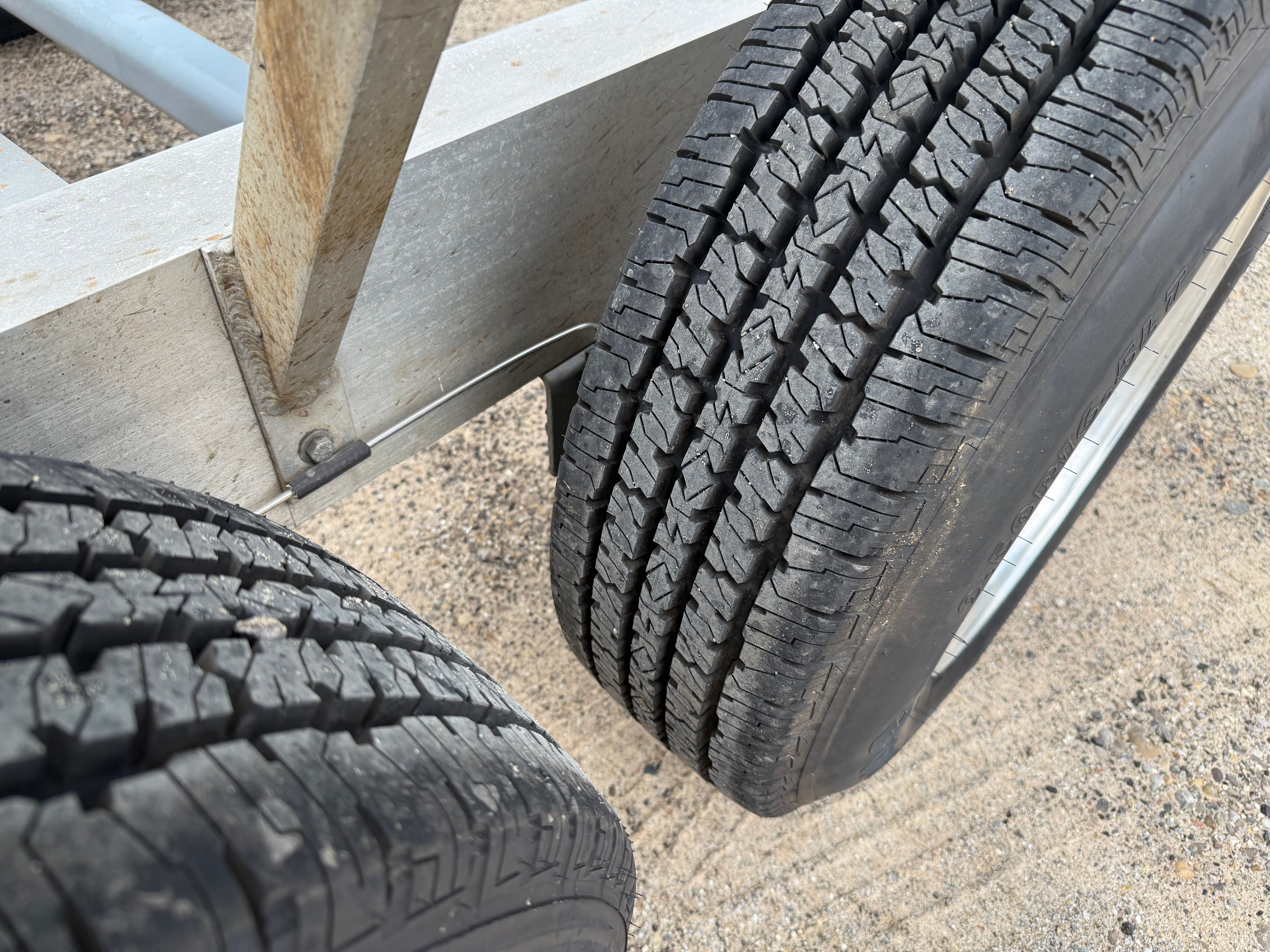 Close-up of trailer tires on sandy ground.