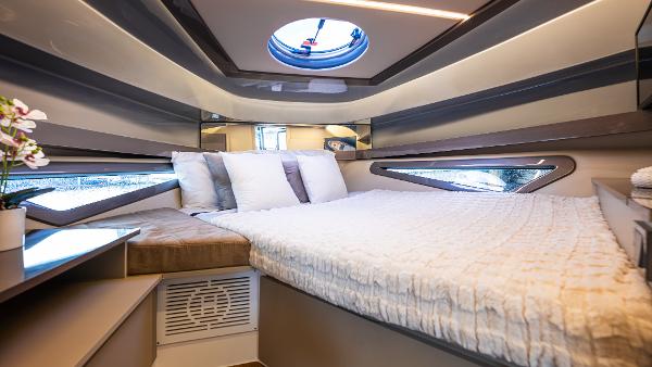 Luxurious cabin interior of 2025 Hanover 415 yacht with modern bedding and porthole.
