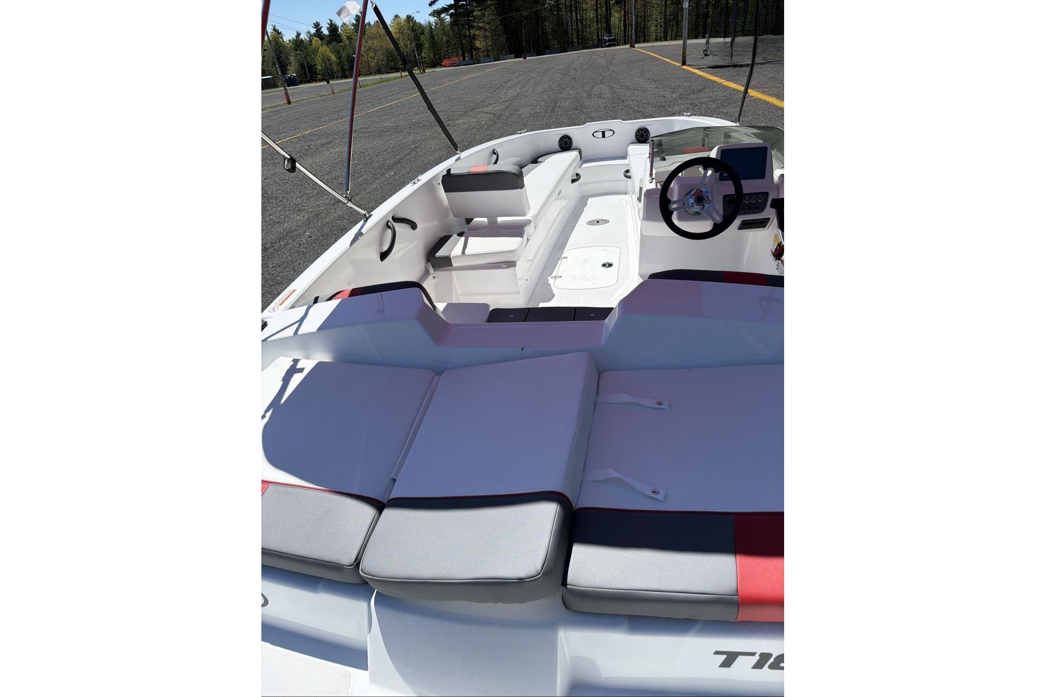 2026 Tahoe T18 boat interior with seating and steering wheel, parked outdoors.