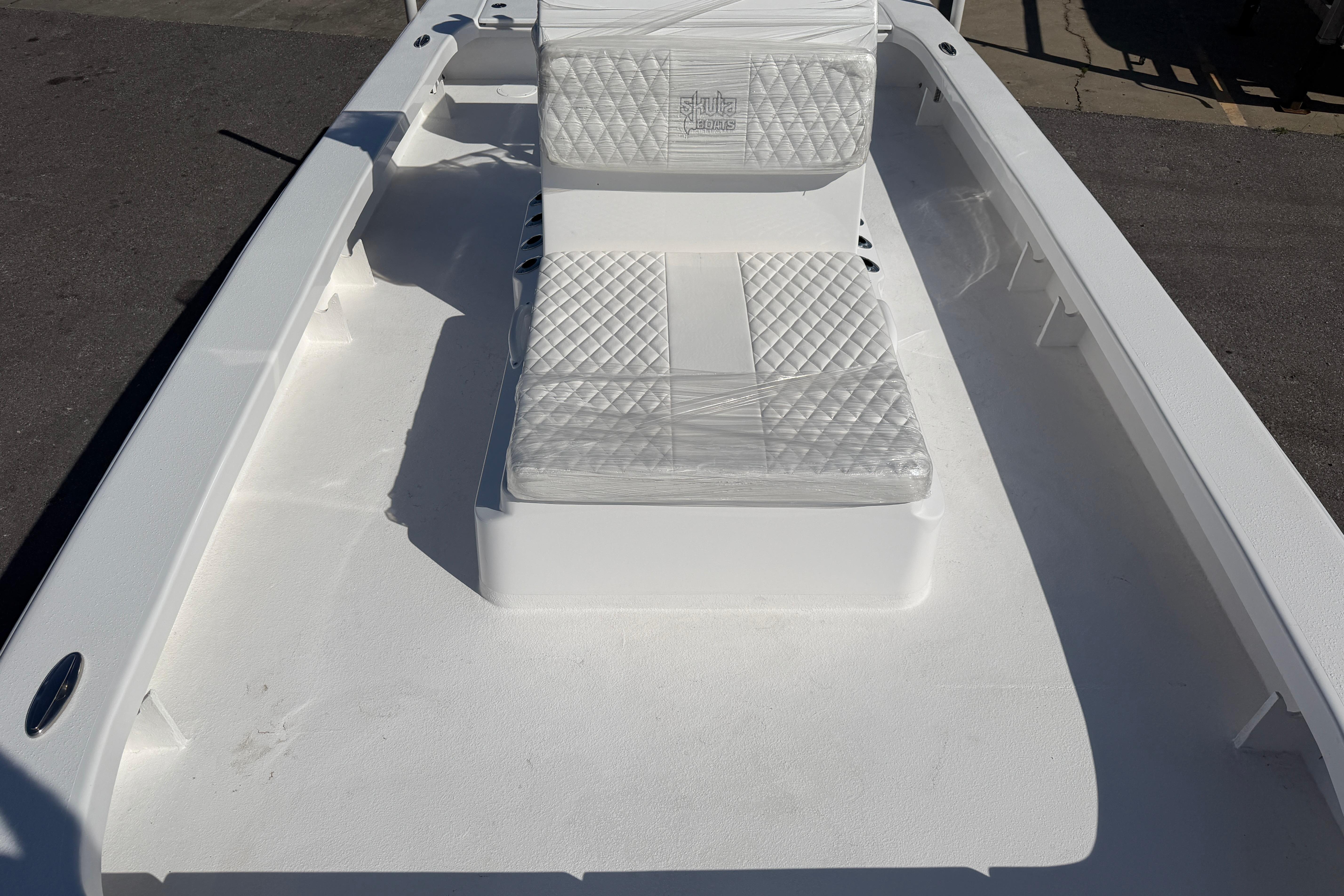 2026 Skuta 24 Cat boat interior with white cushioned seating and sleek design.