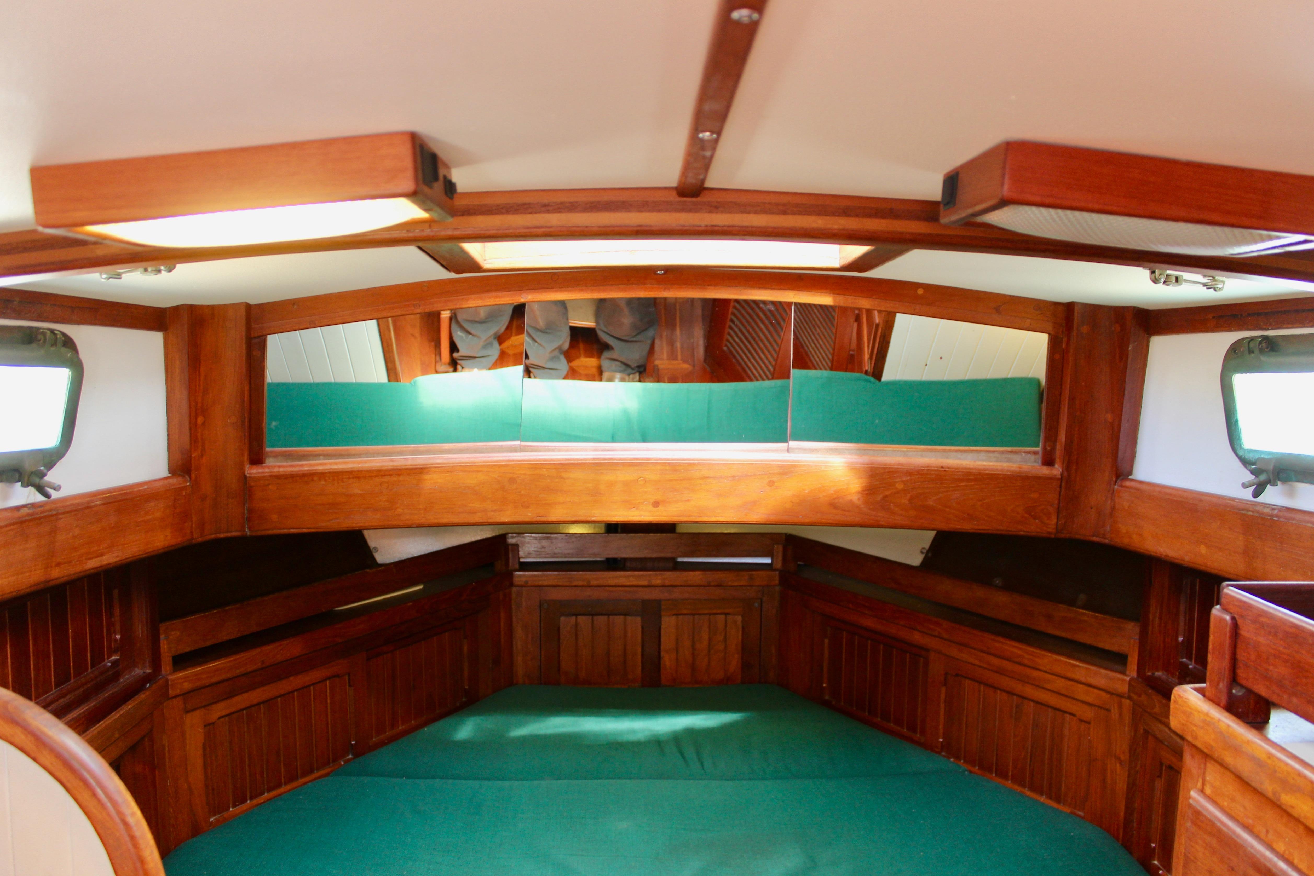 Interior of 1981 Kelly Peterson 46 sailboat with wooden finish and green upholstery.