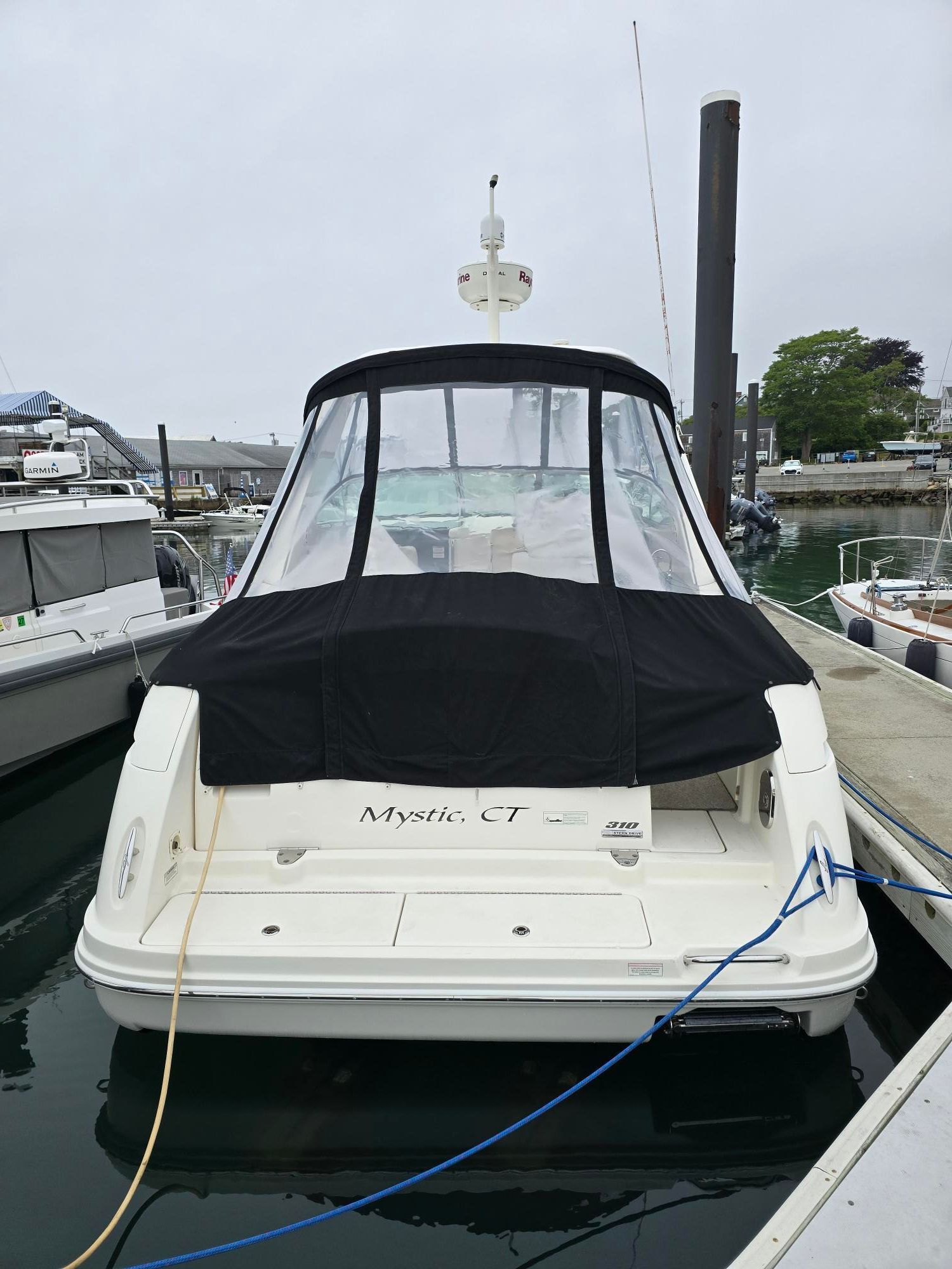 A white boat with a black canopy docked in a marina.