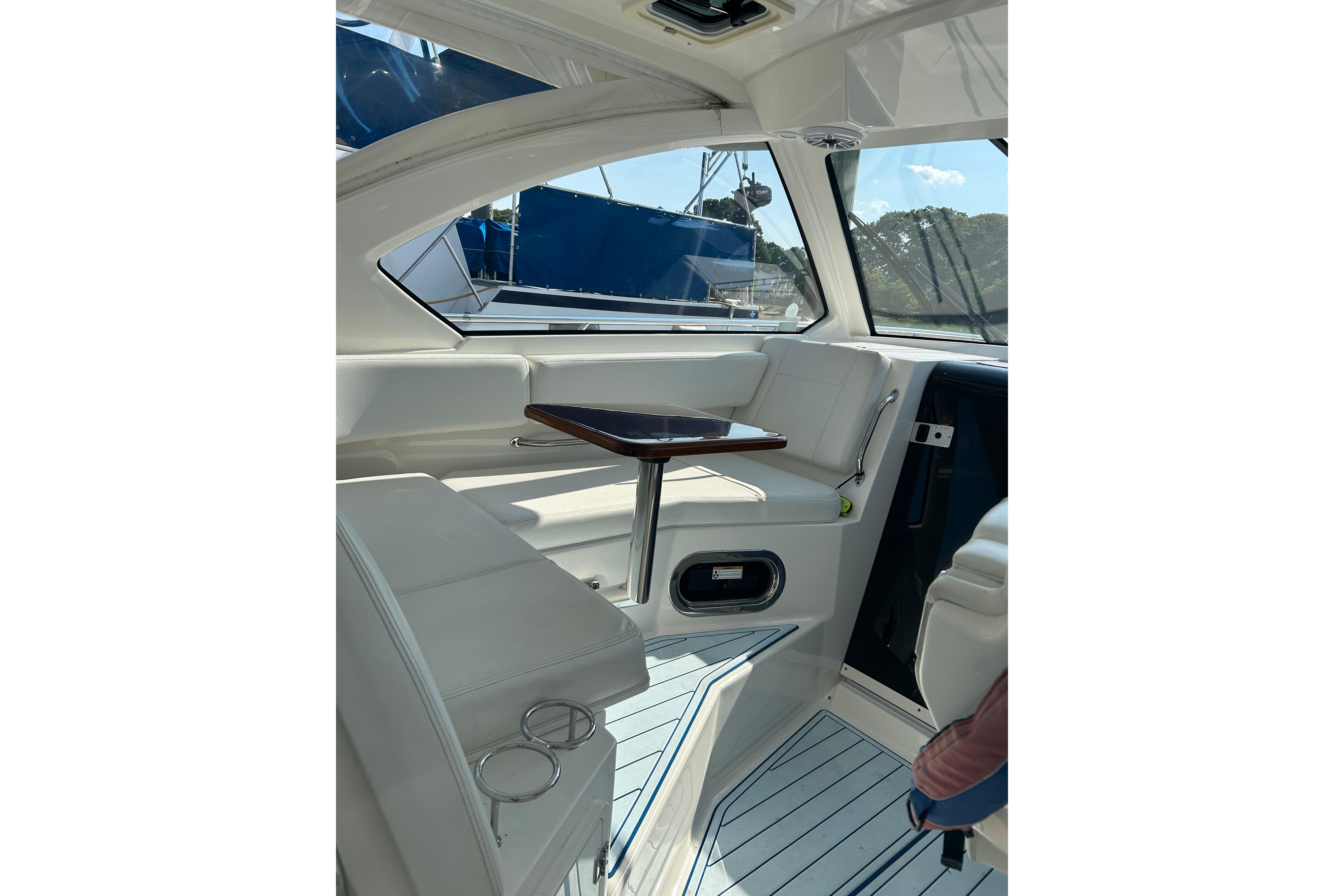 Interior of 2021 Pursuit OS 325 Offshore boat with white seating and wooden table.
