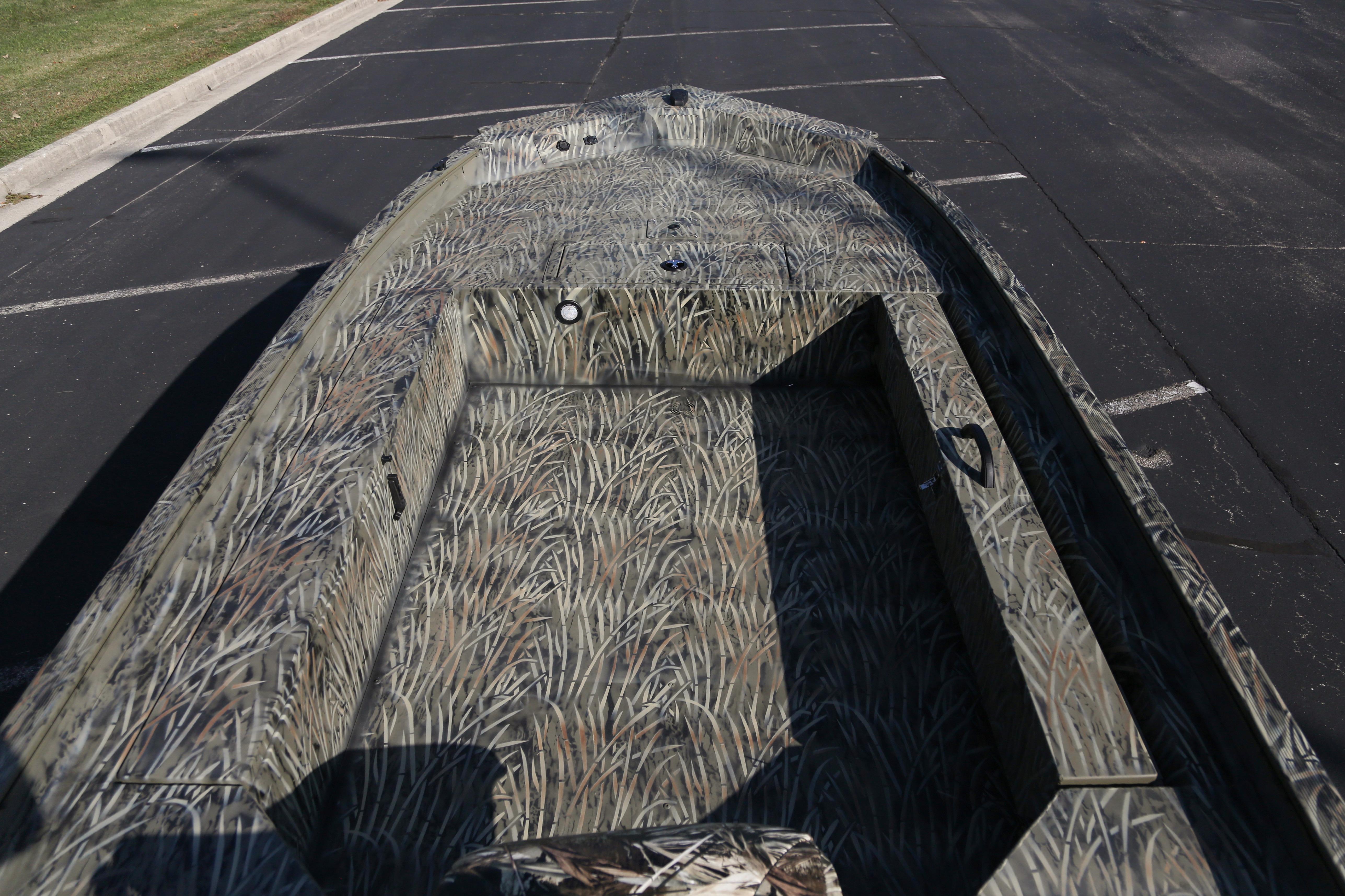 2026 Tracker Grizzly 1654 T Sportsman boat with camouflage design in a parking lot.