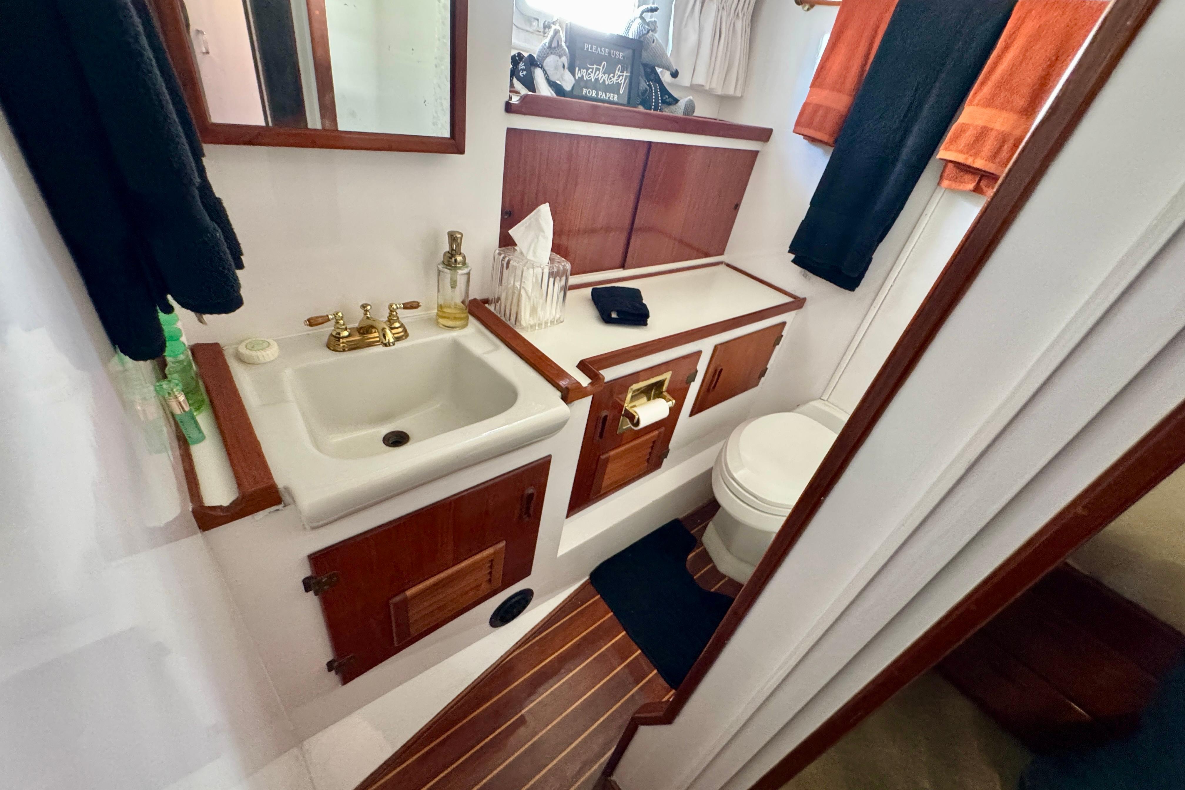 1958 Blanchard Pilothouse bathroom with wooden cabinetry, sink, and toilet.