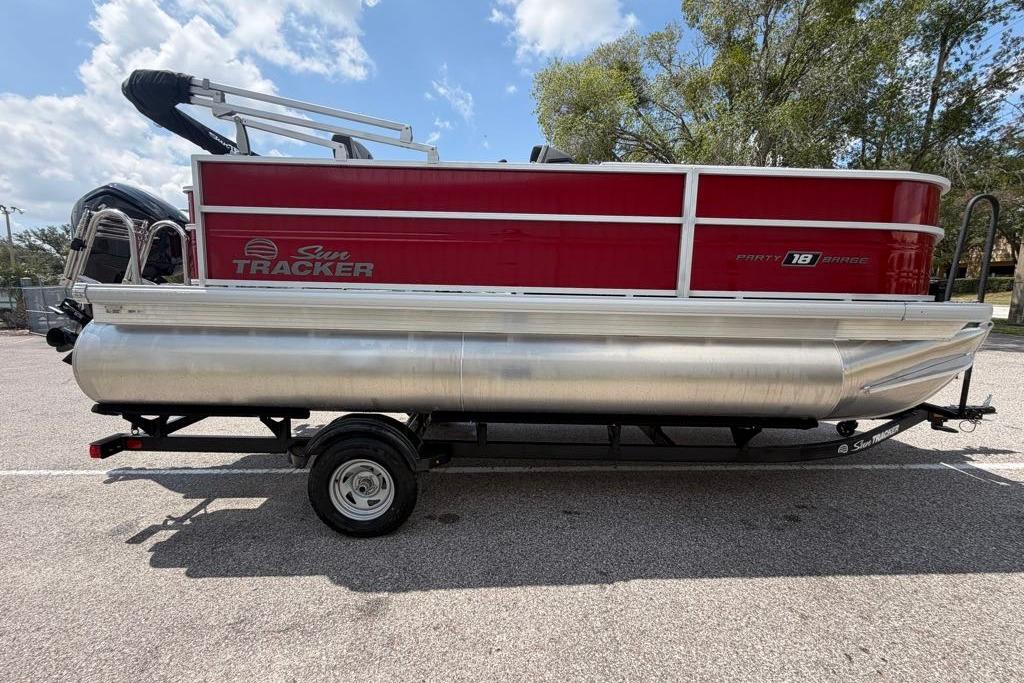 2026 Sun Tracker Party Barge 18 DLX pontoon boat on trailer, parked outdoors.