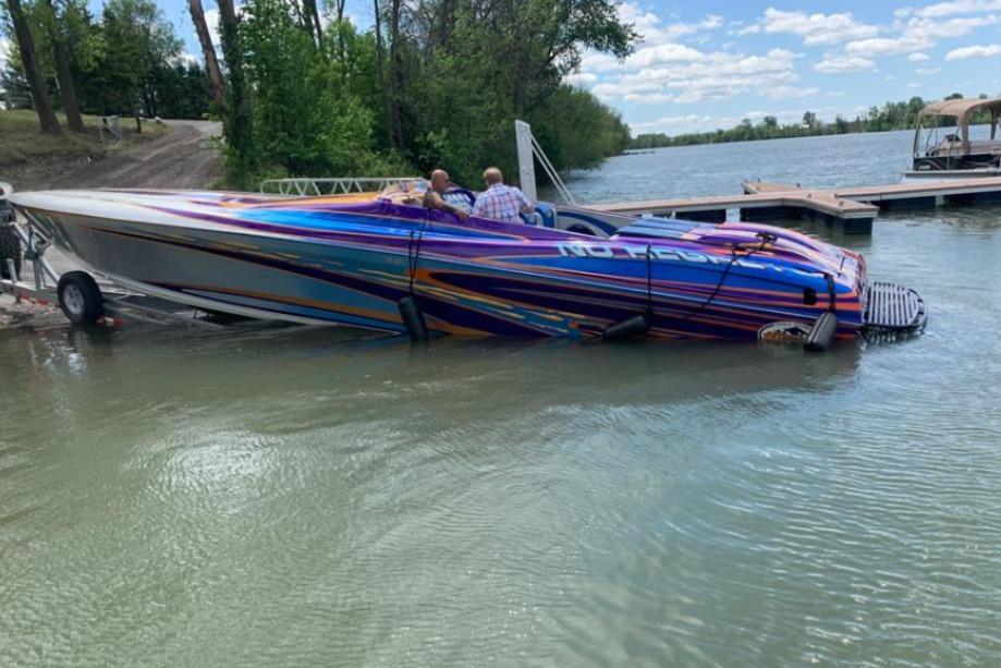 2004 Outerlimits 42 Legacy speedboat with vibrant graphics partially submerged at a dock.