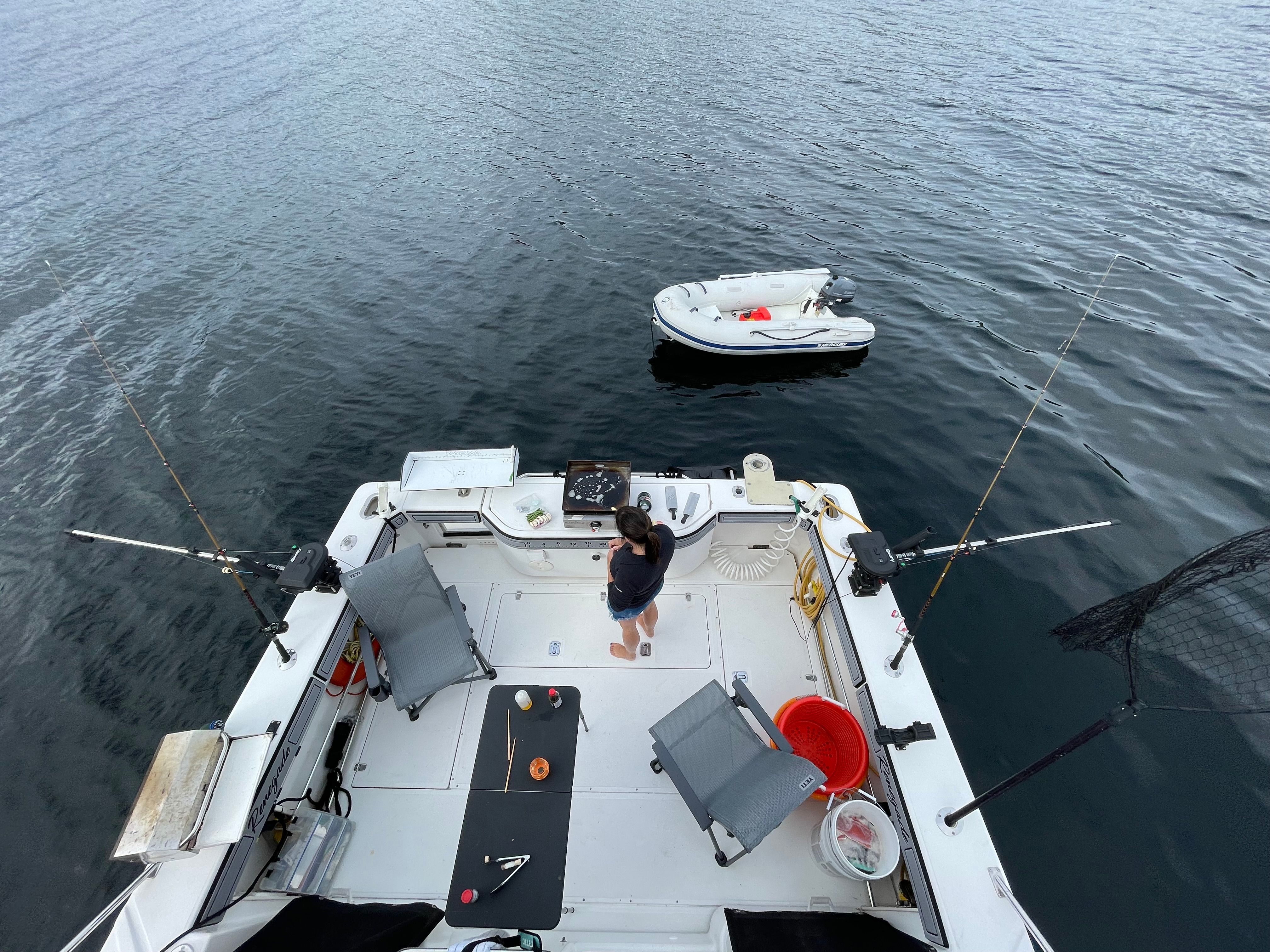 A man stands on the deck of a Boston Whaler 34 Defiance boat, surrounded by fishing rods.