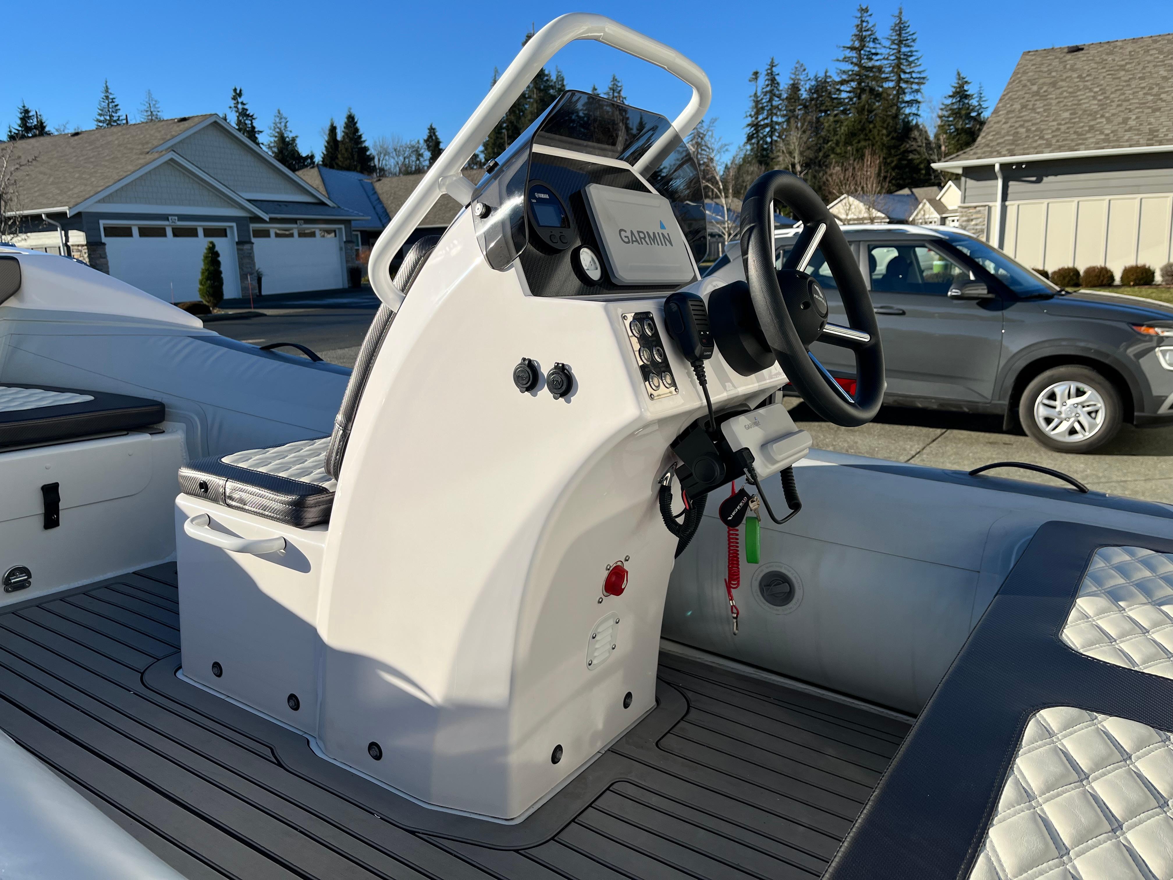 2023 Highfield Sport 420 boat console with steering wheel and controls, parked in residential area.