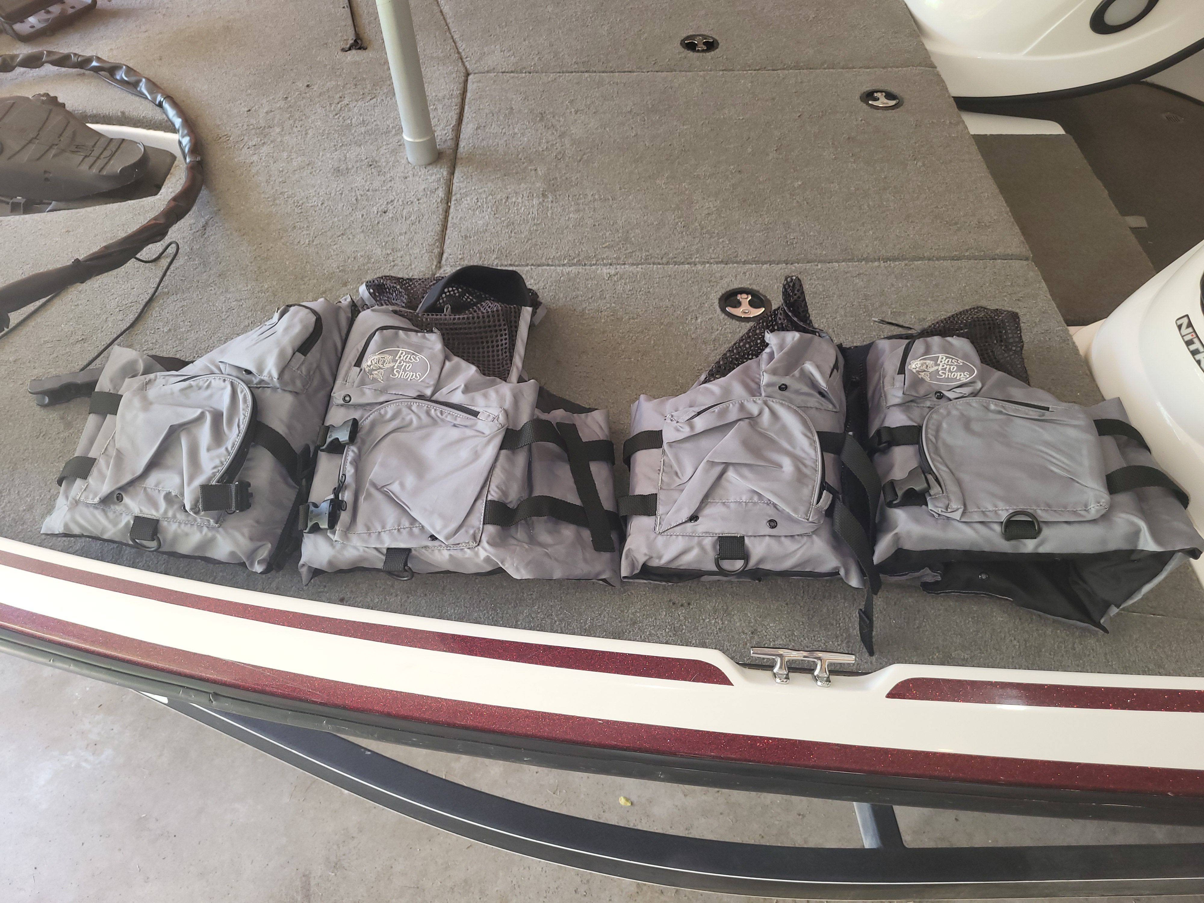 Four gray life jackets are laid out on a boat's deck.