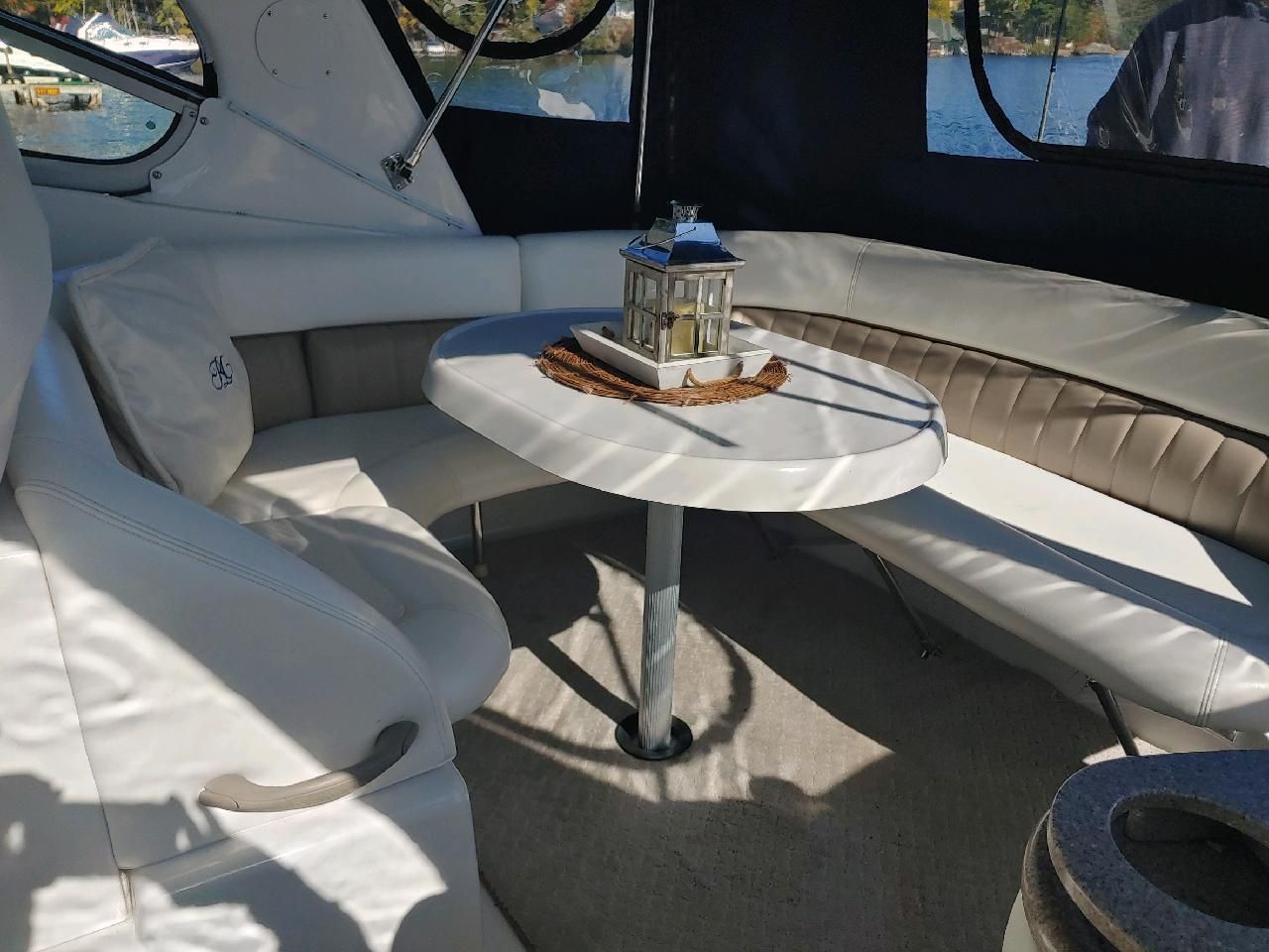 Interior of a boat with white seating area and table, decorated with a lantern.