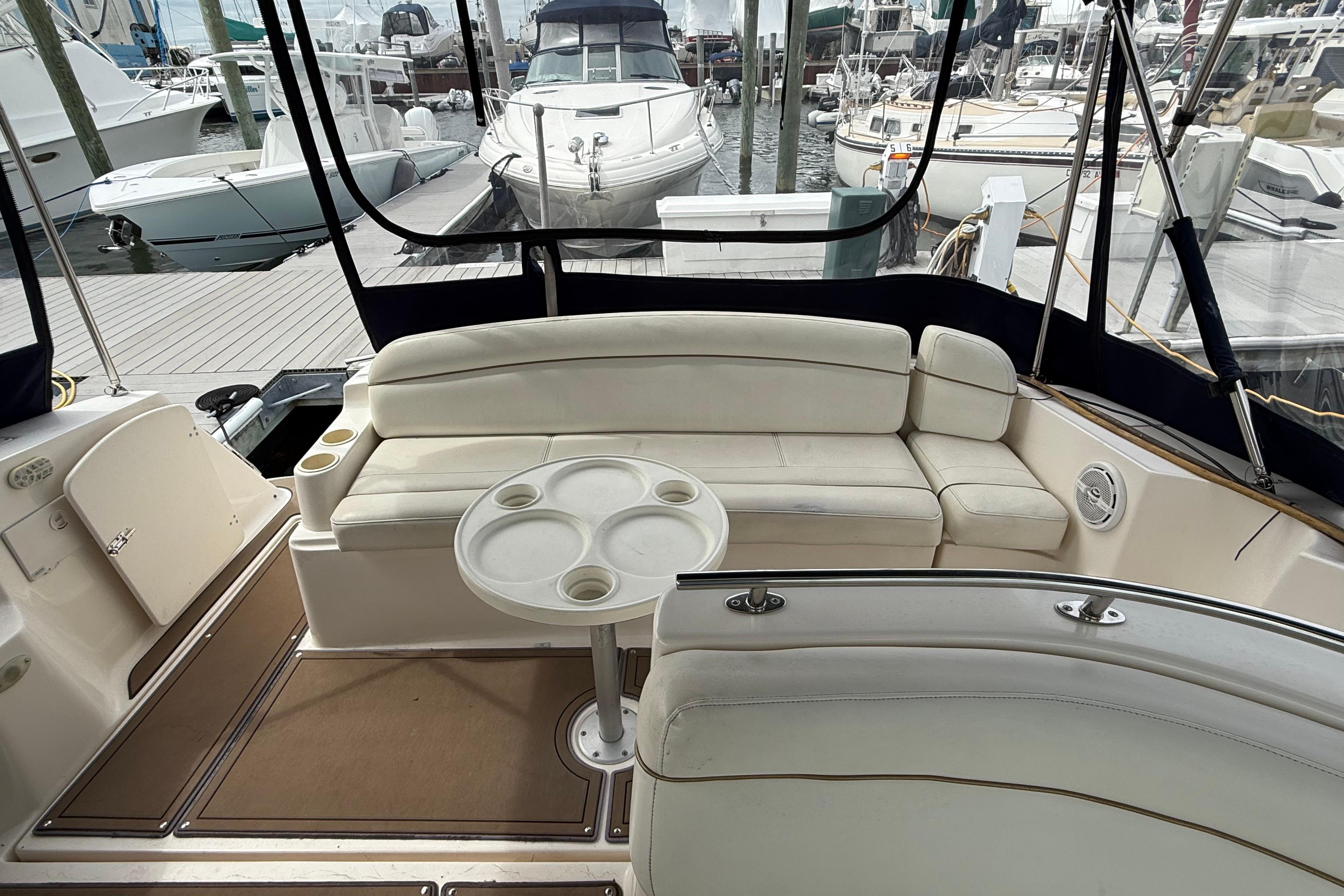 2004 Rinker 342 boat interior with white seating and round table at marina.