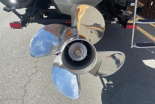Shiny boat propeller of a 2026 Regency 250 DL on pavement background.