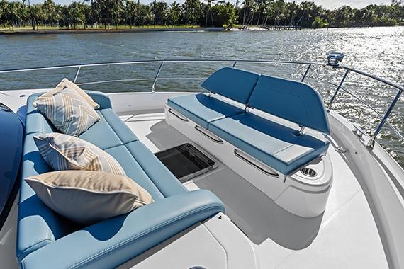 Luxurious 2026 Cruisers 50 Fly yacht deck with plush seating and scenic water view.