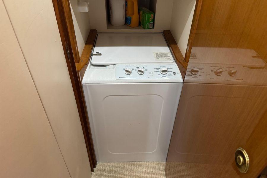 Laundry area inside 2002 Viking 61 Enclosed Bridge yacht, featuring a compact washing machine.