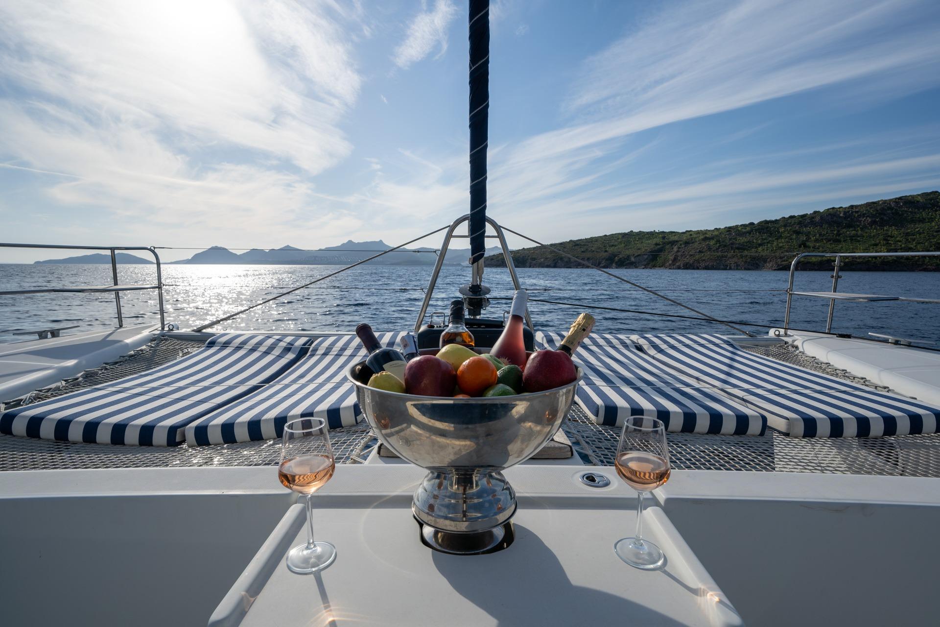 Lagoon 440 catamaran deck with fruit bowl, wine glasses, and ocean view, 2005 model.