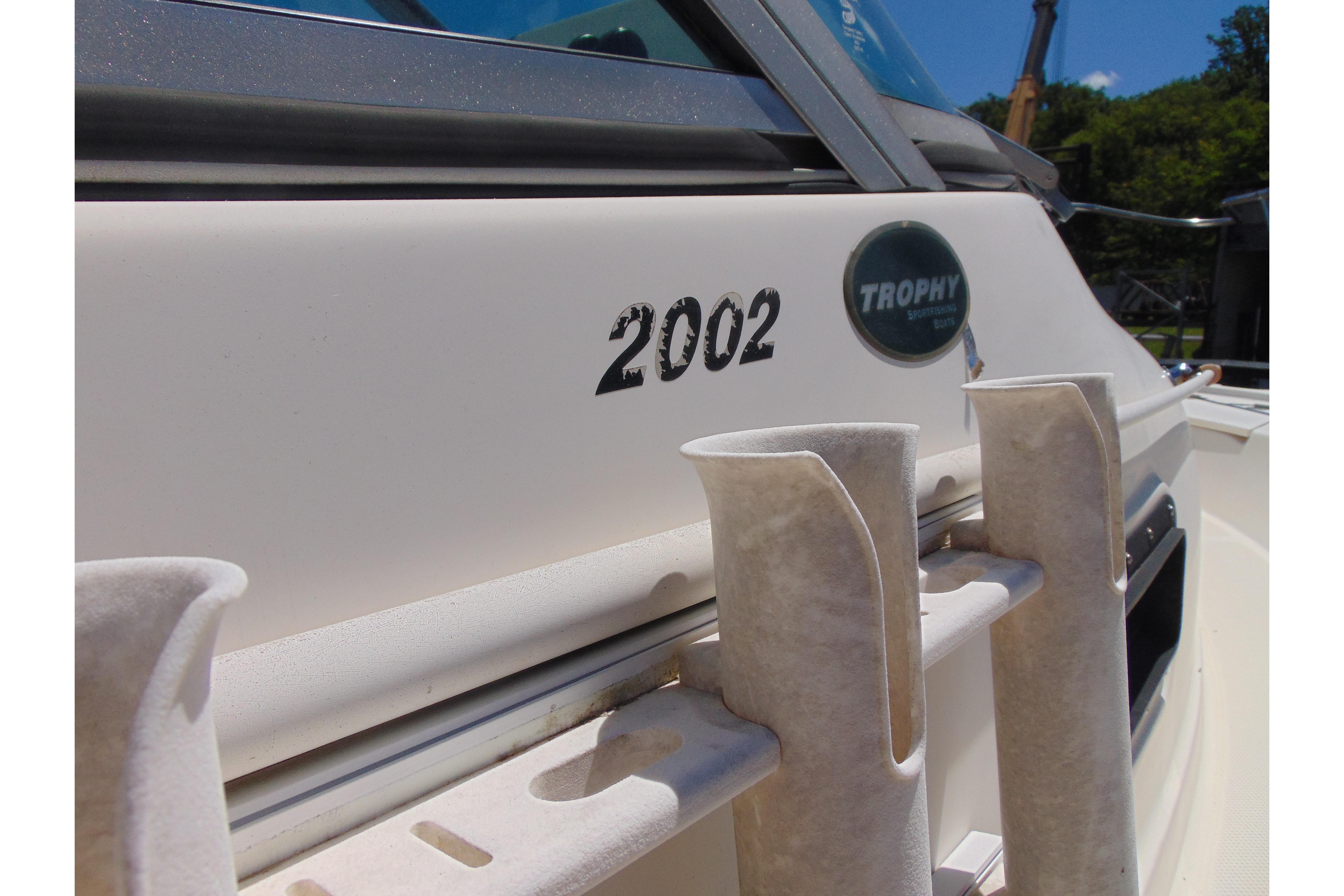 2002 Trophy Walkaround boat with rod holders and logo in sunlight.