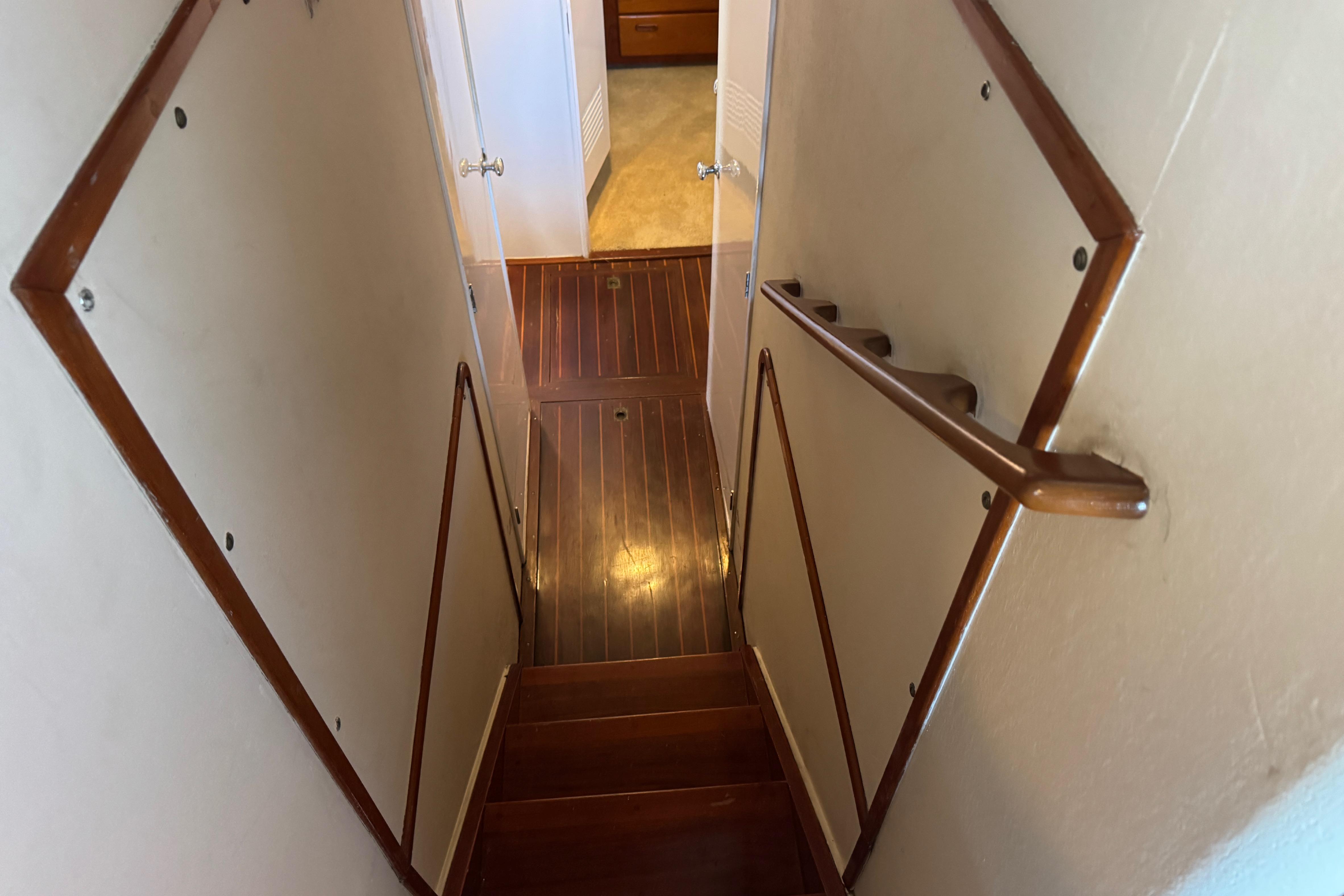Staircase inside 1958 Blanchard Pilothouse boat with wooden handrails and flooring.