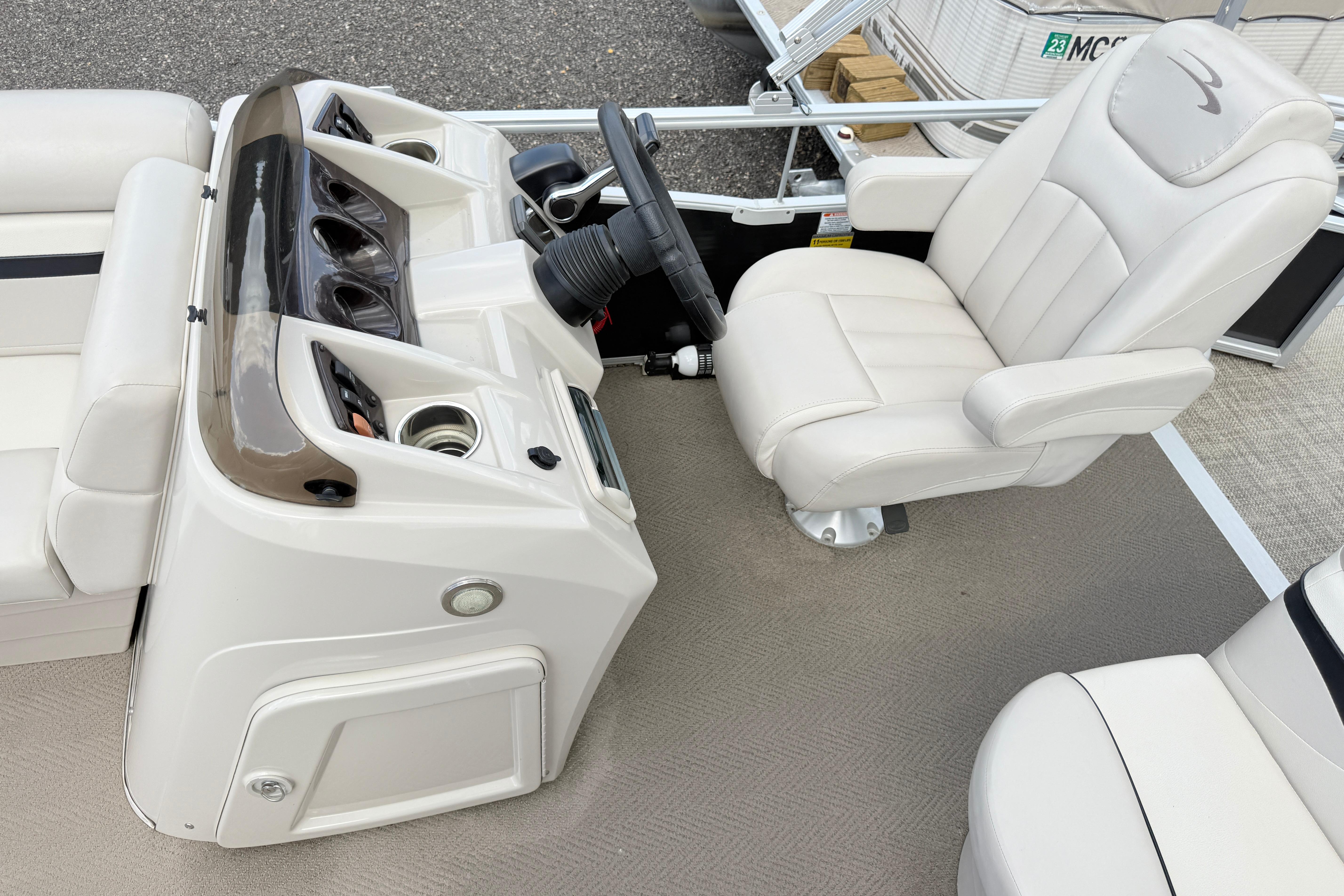 Captain's chair and helm of a 2015 Bennington 24SSLX pontoon boat, featuring a sleek dashboard design.