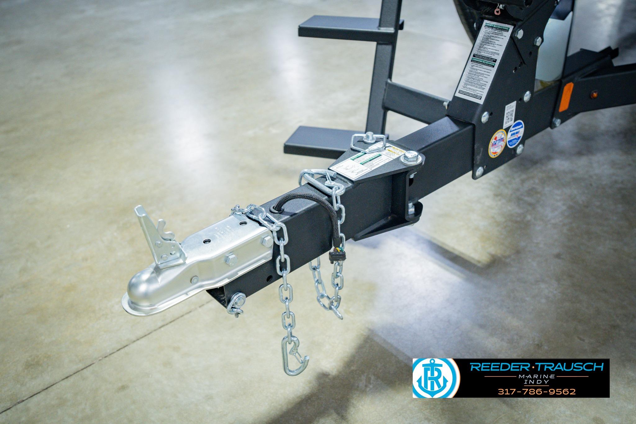 Trailer hitch of 2026 Lund 1775 Impact XS boat, secured with chains, on showroom floor.