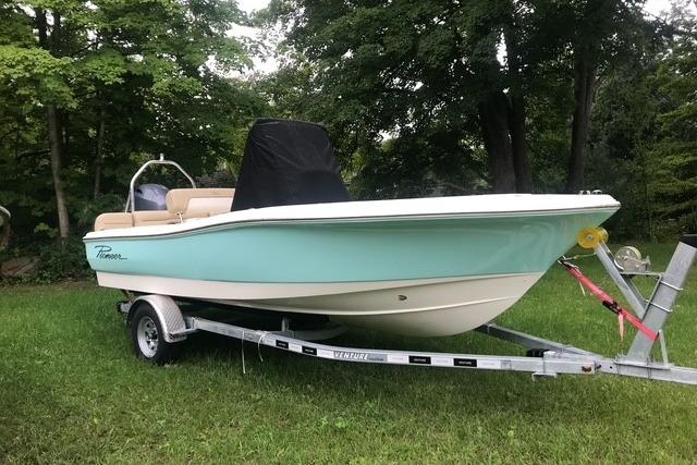 2026 Pioneer 180 Islander boat on trailer, parked on grass with trees in background.
