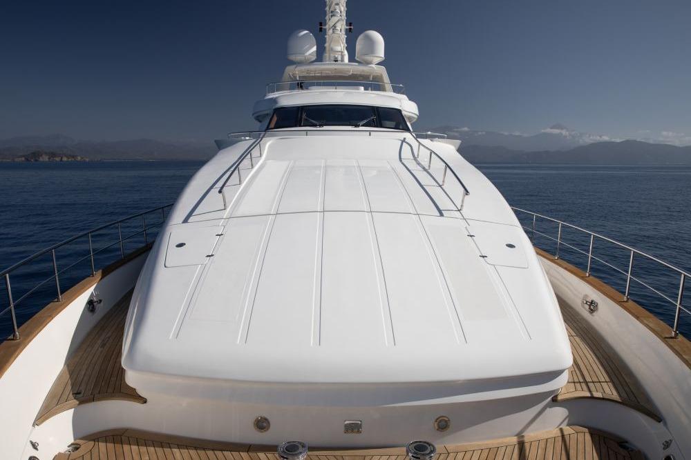 Luxurious 2009 CRN 129 yacht on calm sea with mountainous backdrop.