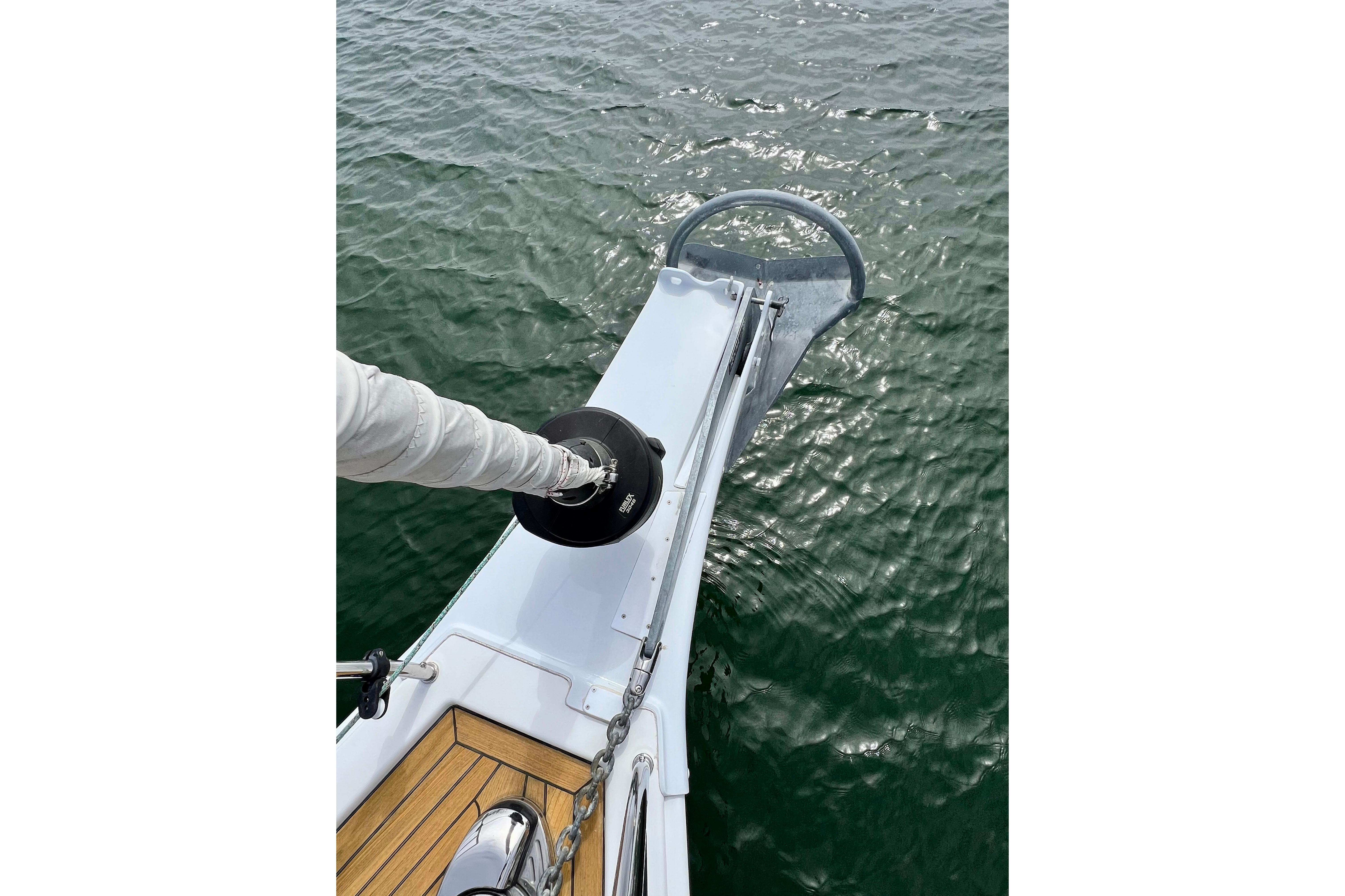 Bow of 2016 Hanse 455 yacht with anchor over calm water.