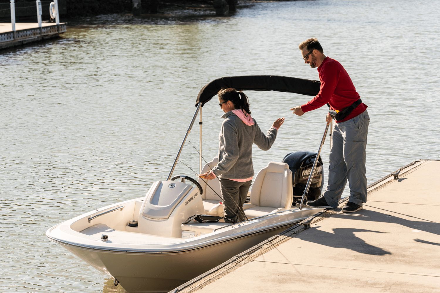 Two people boarding a small motorboat at the dock.