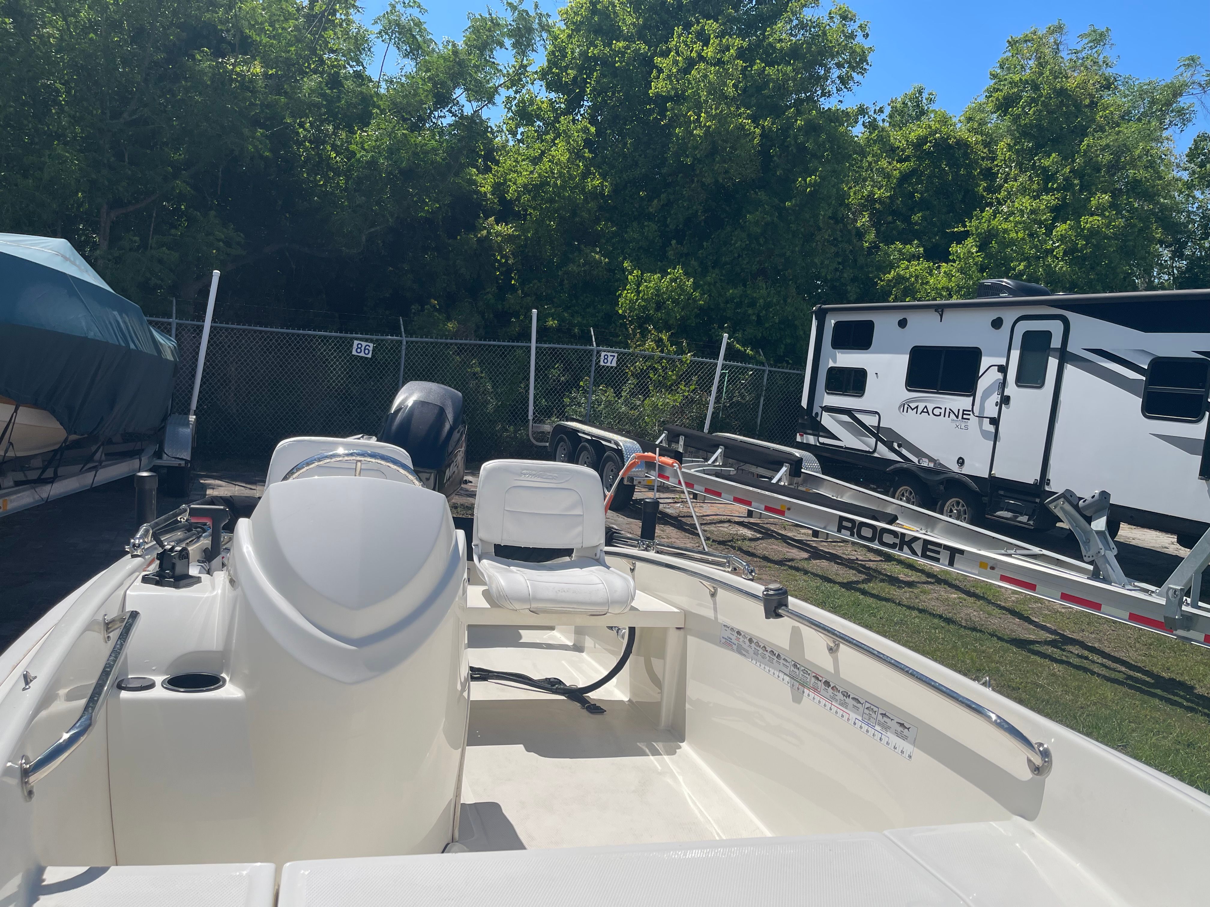 A 2017 Boston Whaler 130 Super Sport is on a trailer next to a camper.