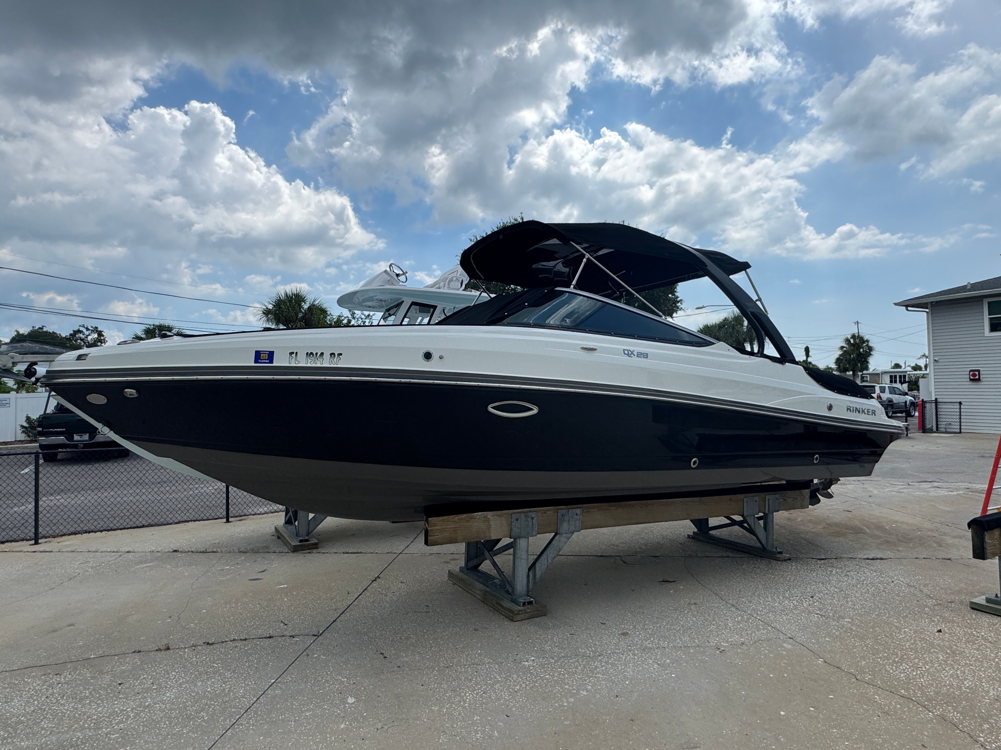 2017 Rinker QX29 BR boat on a stand under cloudy sky.
