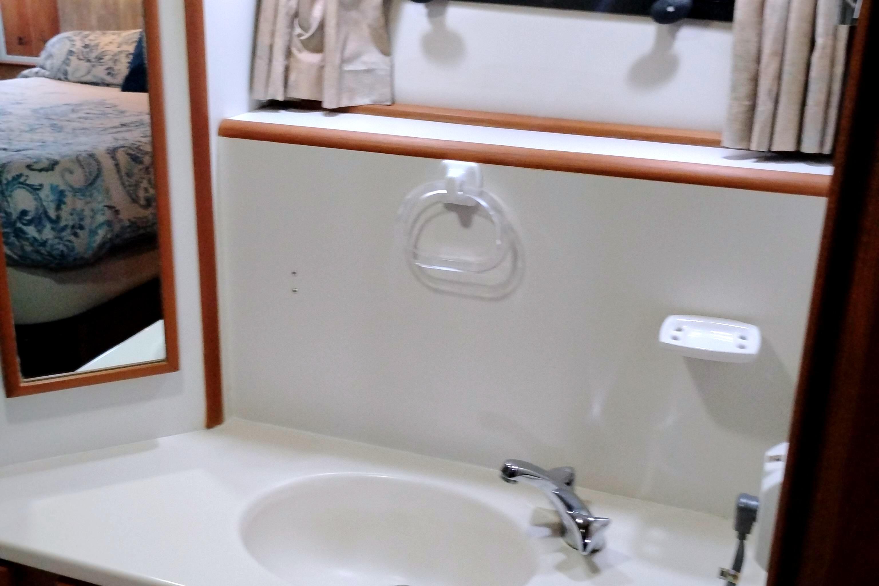 Bathroom sink area in a 1991 Californian 52 Cockpit Motor Yacht, featuring a mirror and faucet.