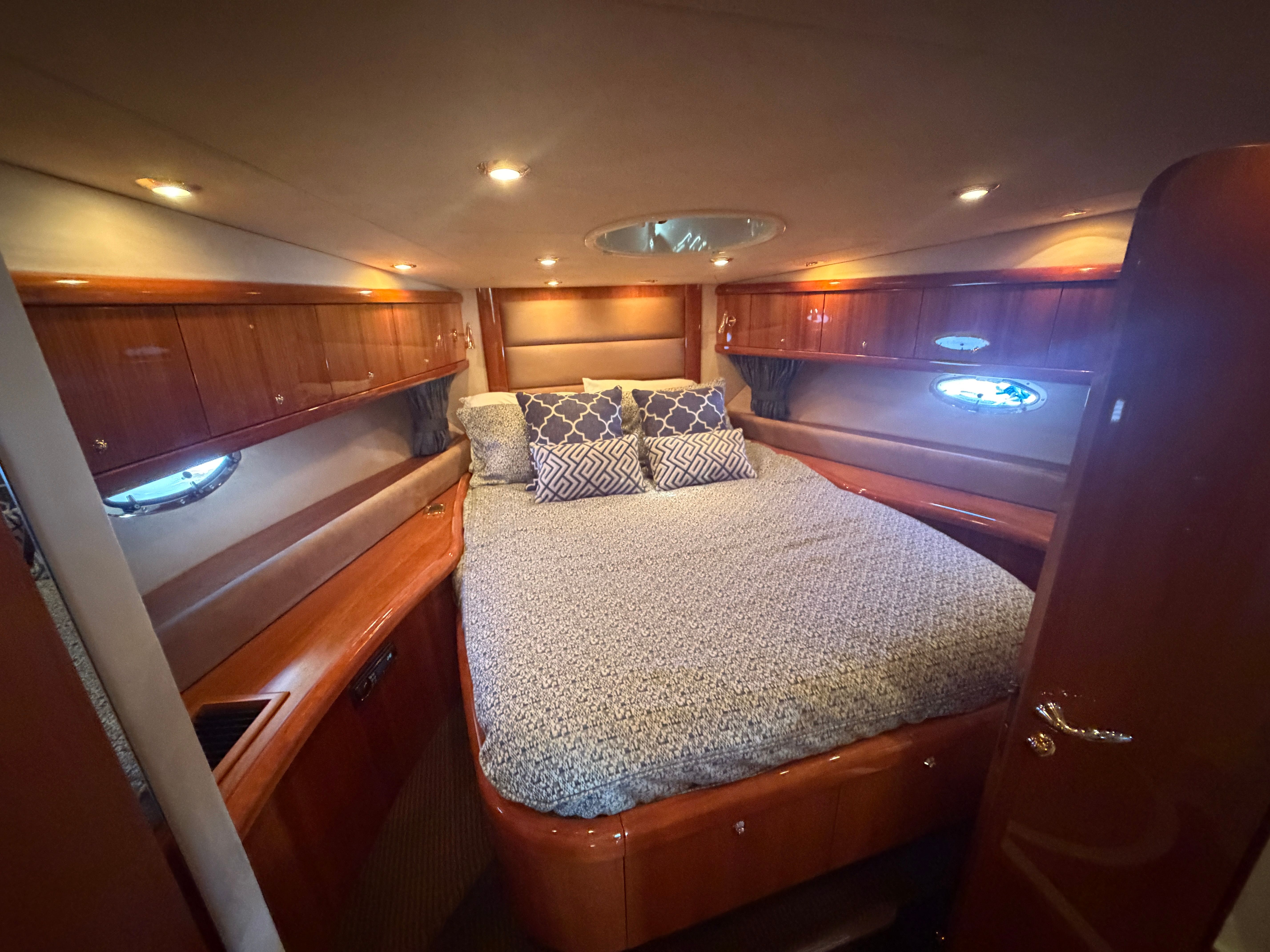 Luxurious cabin with a large bed, wooden furnishings, and porthole windows.