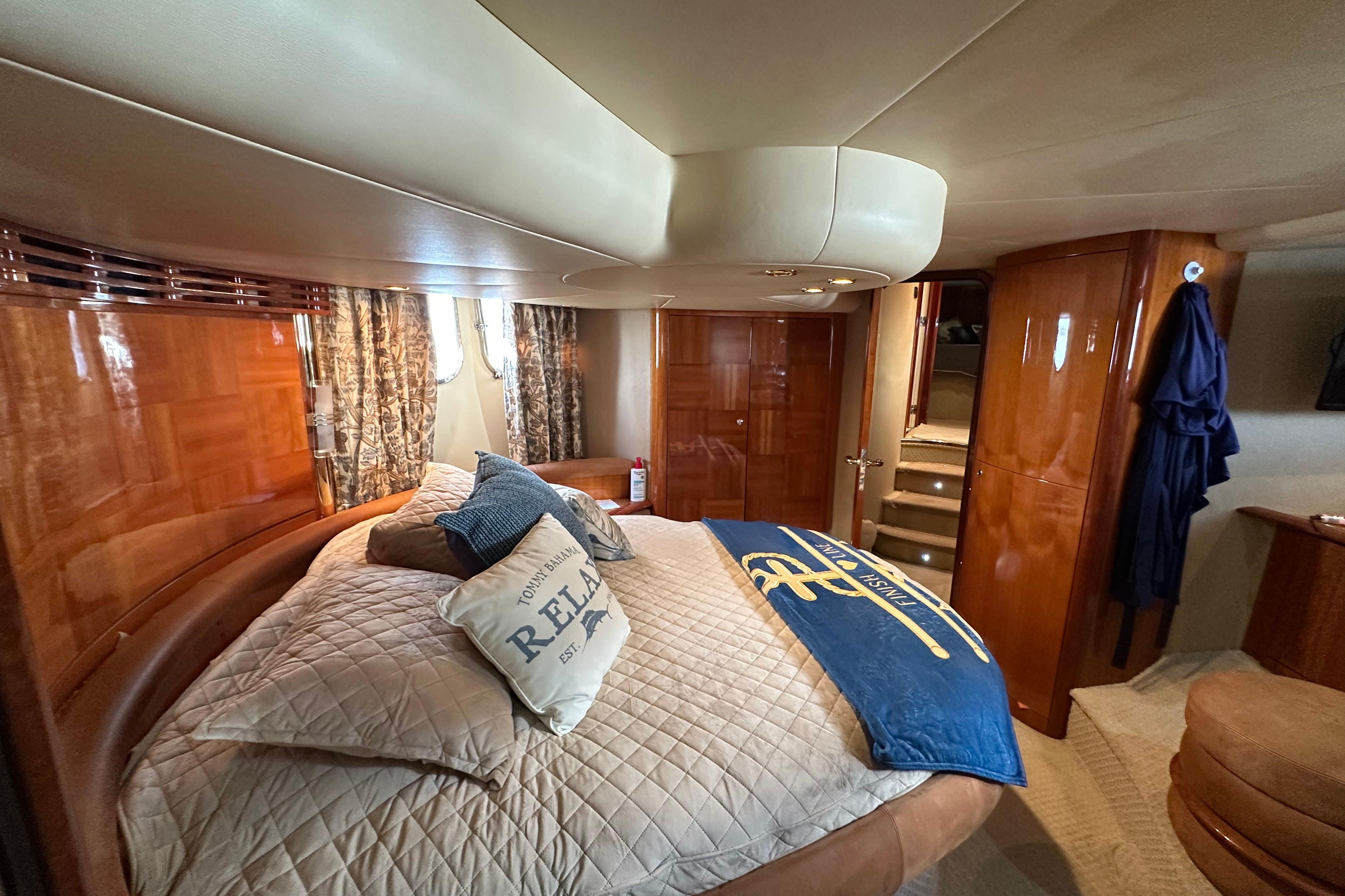 Luxurious bedroom interior of a 2004 Azimut 55E yacht with elegant wood finishes.