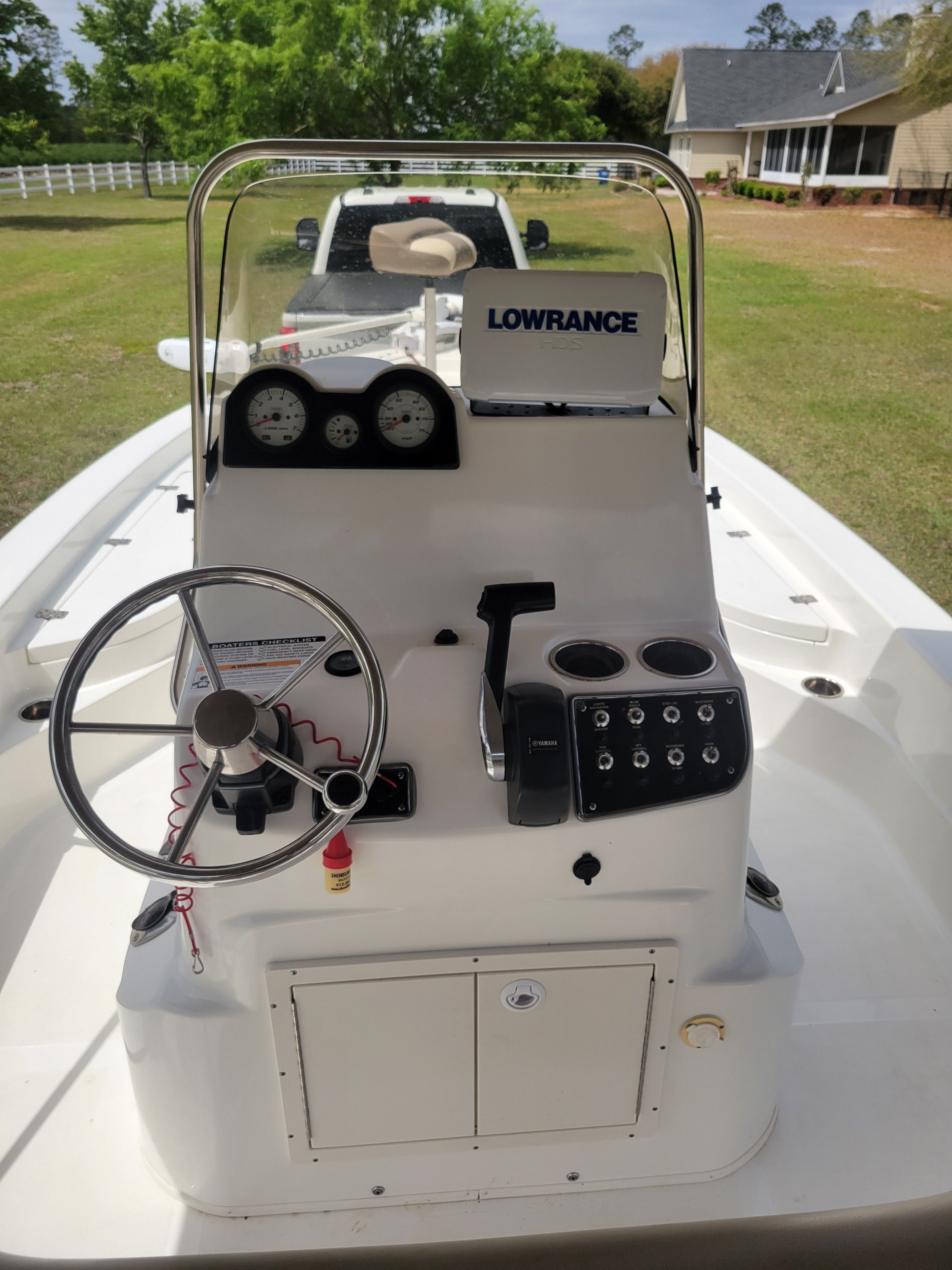The boat is on land on a trailer, featuring a helm and instruments.