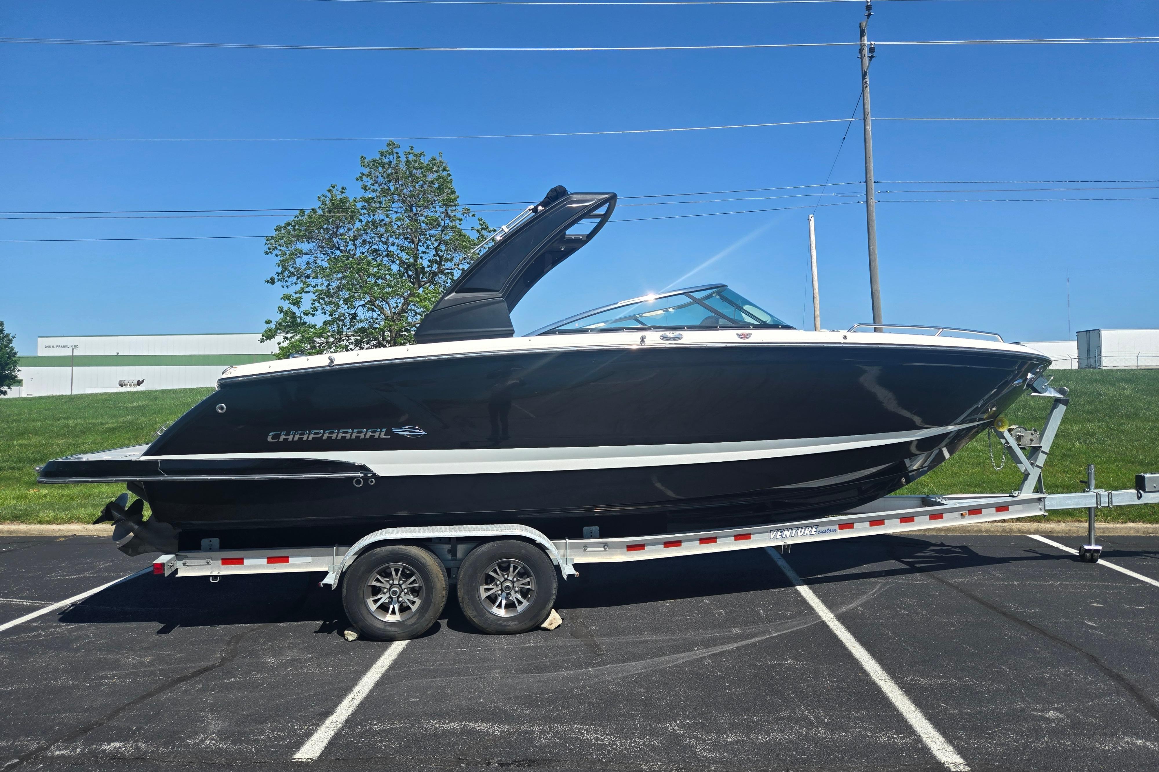 2018 Chaparral 267 SSX boat on trailer, parked outdoors under clear blue sky.